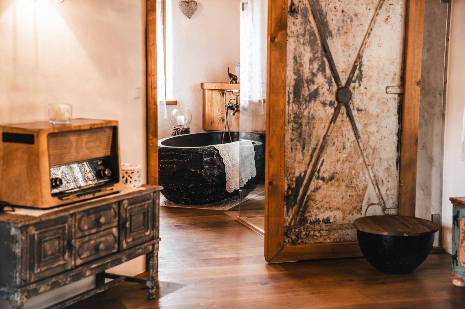 Rustikaler Flur mit antiken Möbeln und Zugang zu einem Badezimmer mit Badewanne.