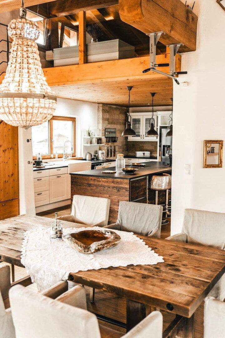 Rustikaler Essbereich mit Holztisch und Blick auf die offene, moderne Küche.