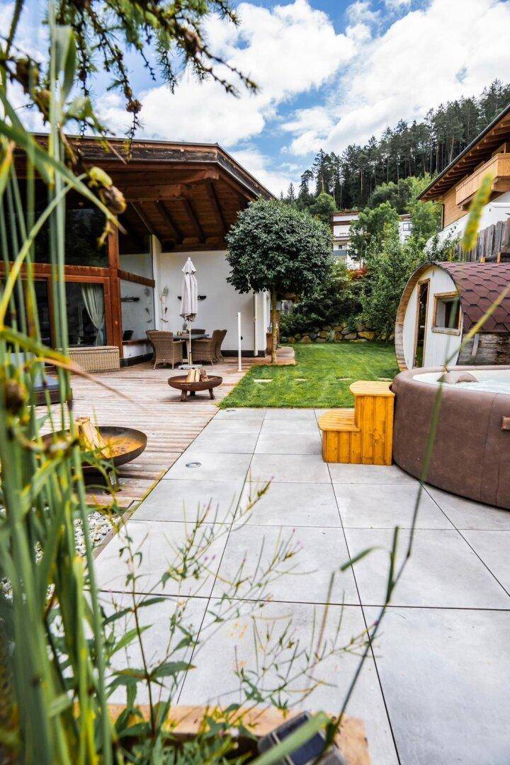 Außenbereich mit Whirlpool, gepflasterter Terrasse und gepflegtem Rasen.