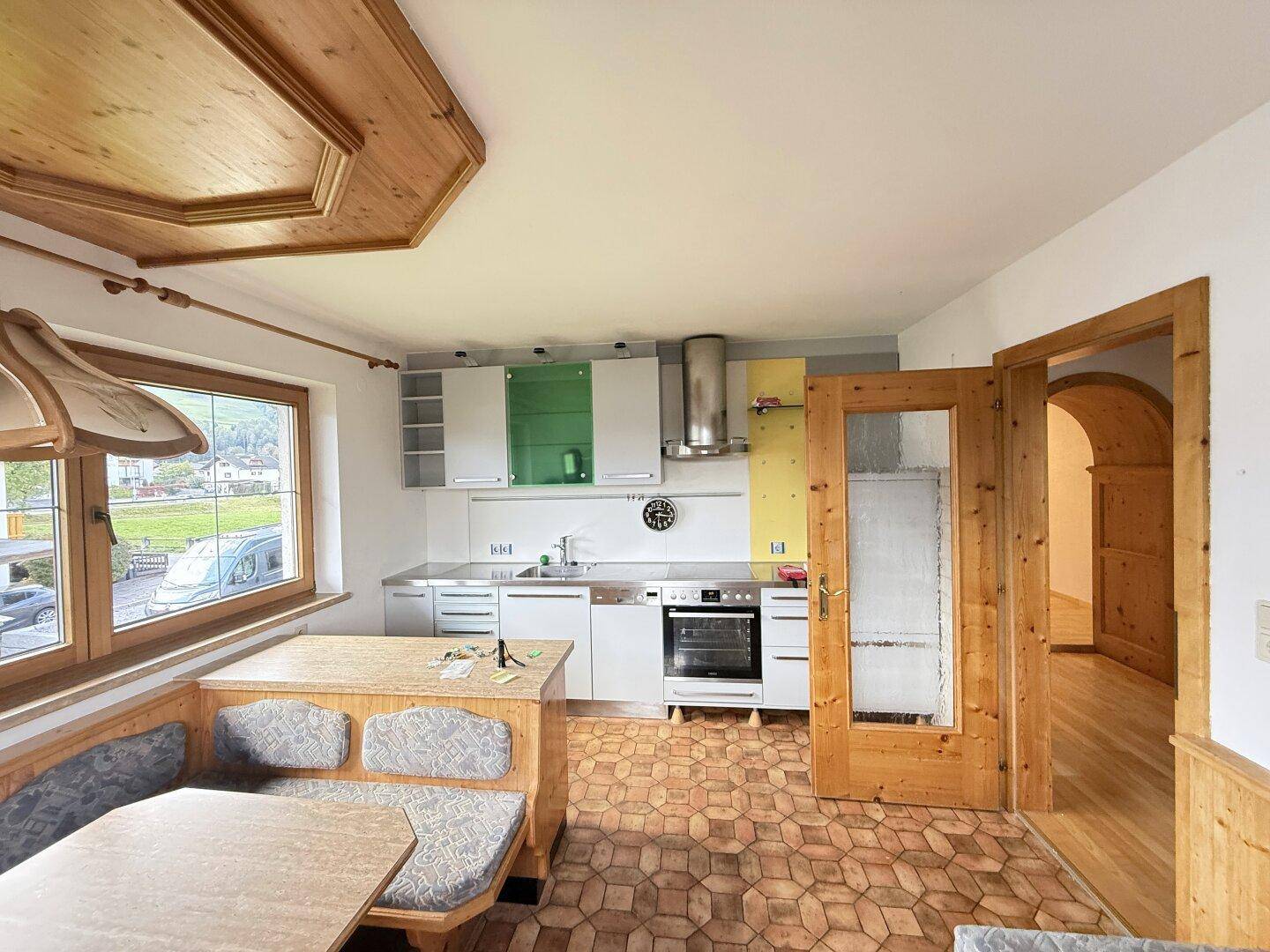 Traditionelle Wohnküche mit Holzboden, Einbauküche und gemütlicher Eckbank mit Blick ins Grüne.