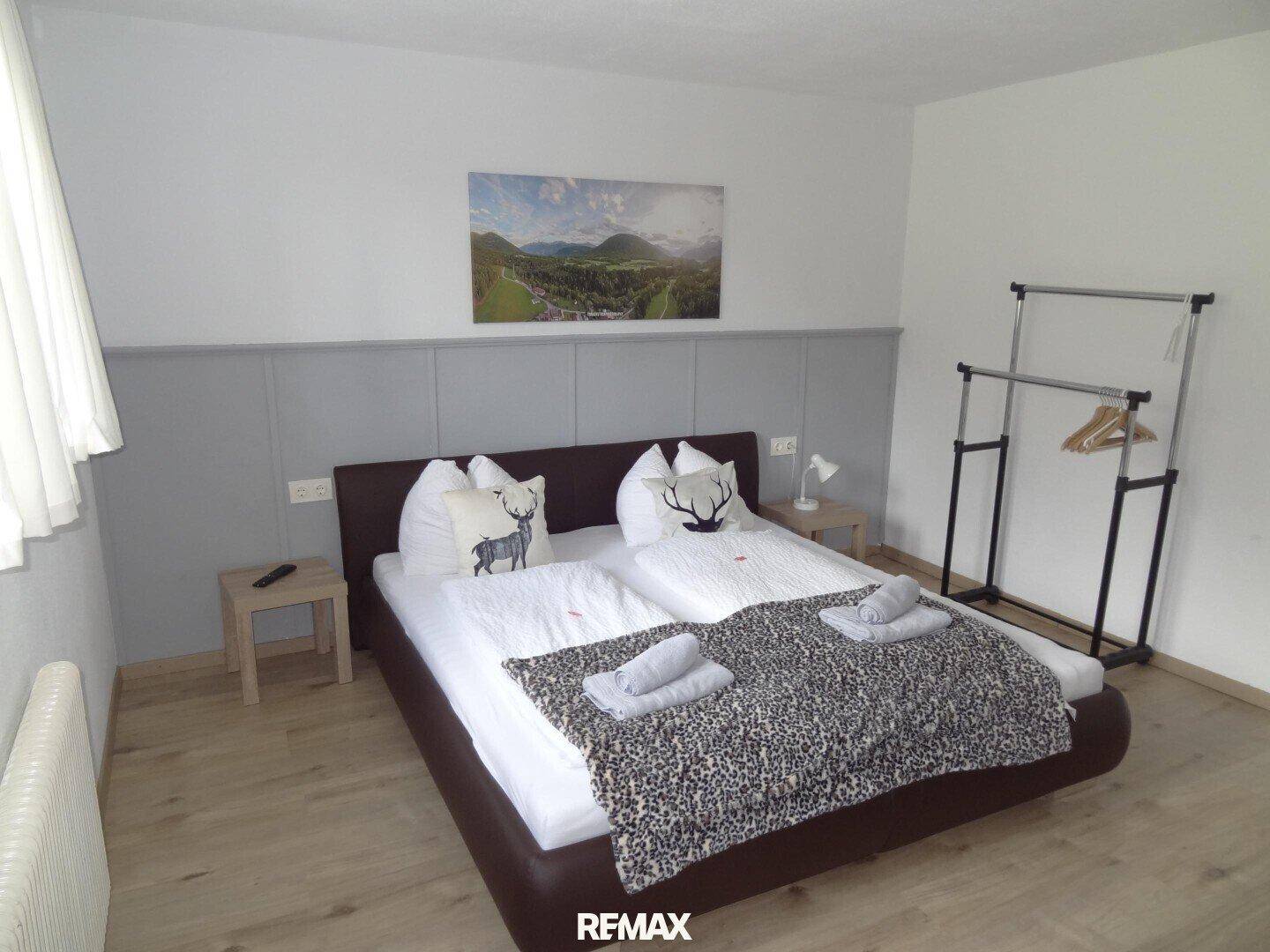 Helles Schlafzimmer mit Doppelbett, Laminatboden und einem praktischen Kleiderständer, gut gepflegt.