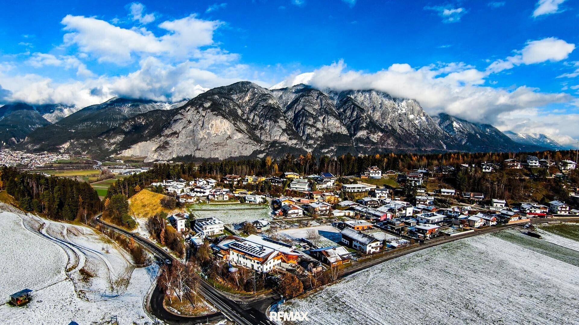 Malerische Luftaufnahme einer Siedlung in einer verschneiten Berglandschaft.