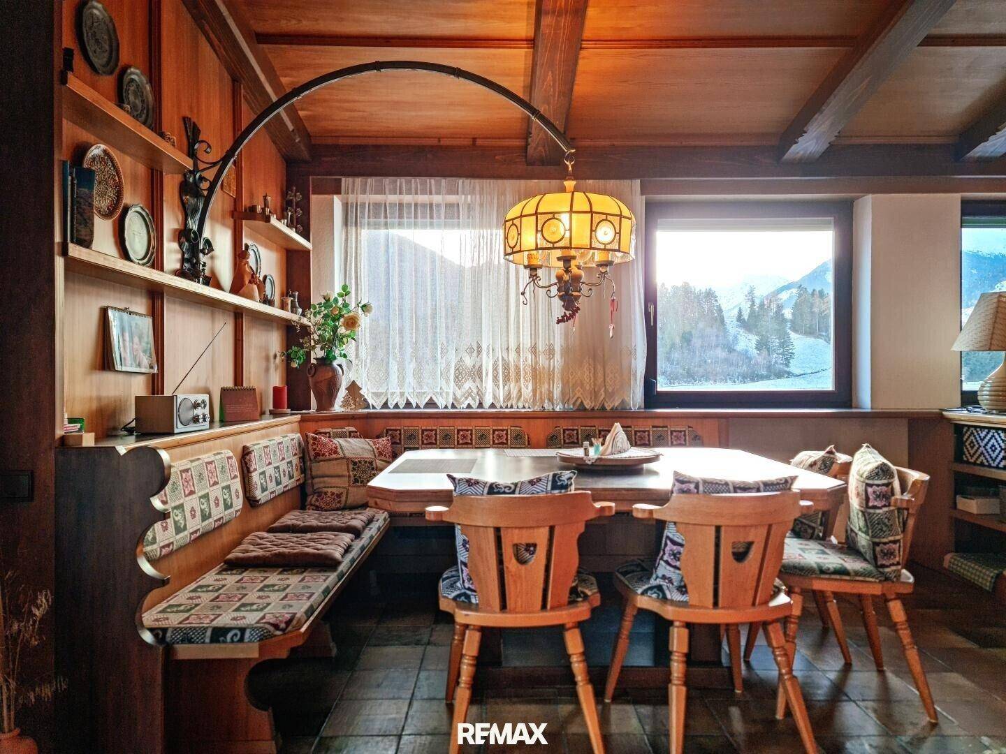 Traditioneller Essbereich mit Holztisch, Eckbank und Blick auf die verschneite Winterlandschaft.