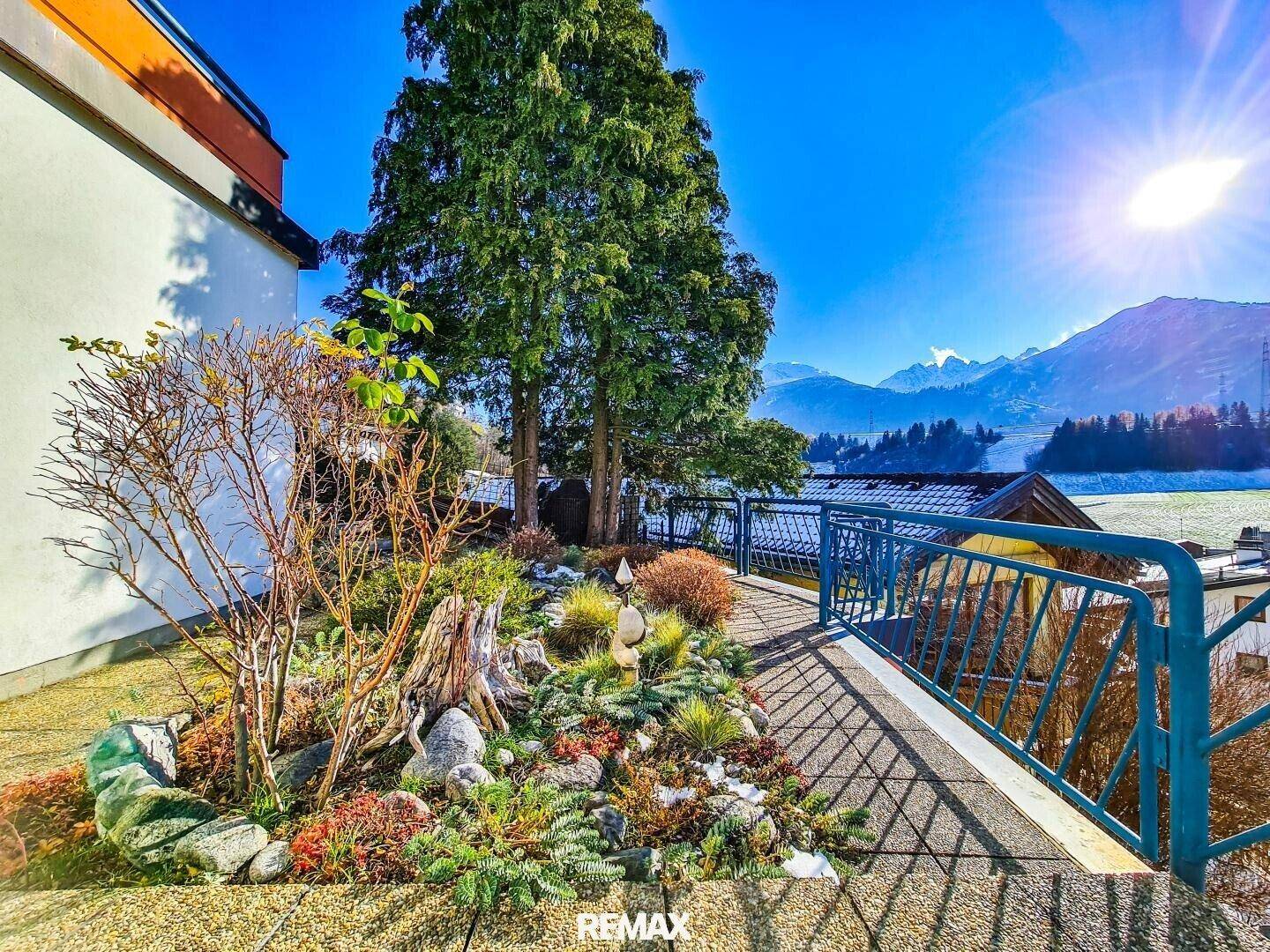 Mediterraner Steingarten mit verschiedenen Pflanzen und Blick auf die umliegenden Berge.