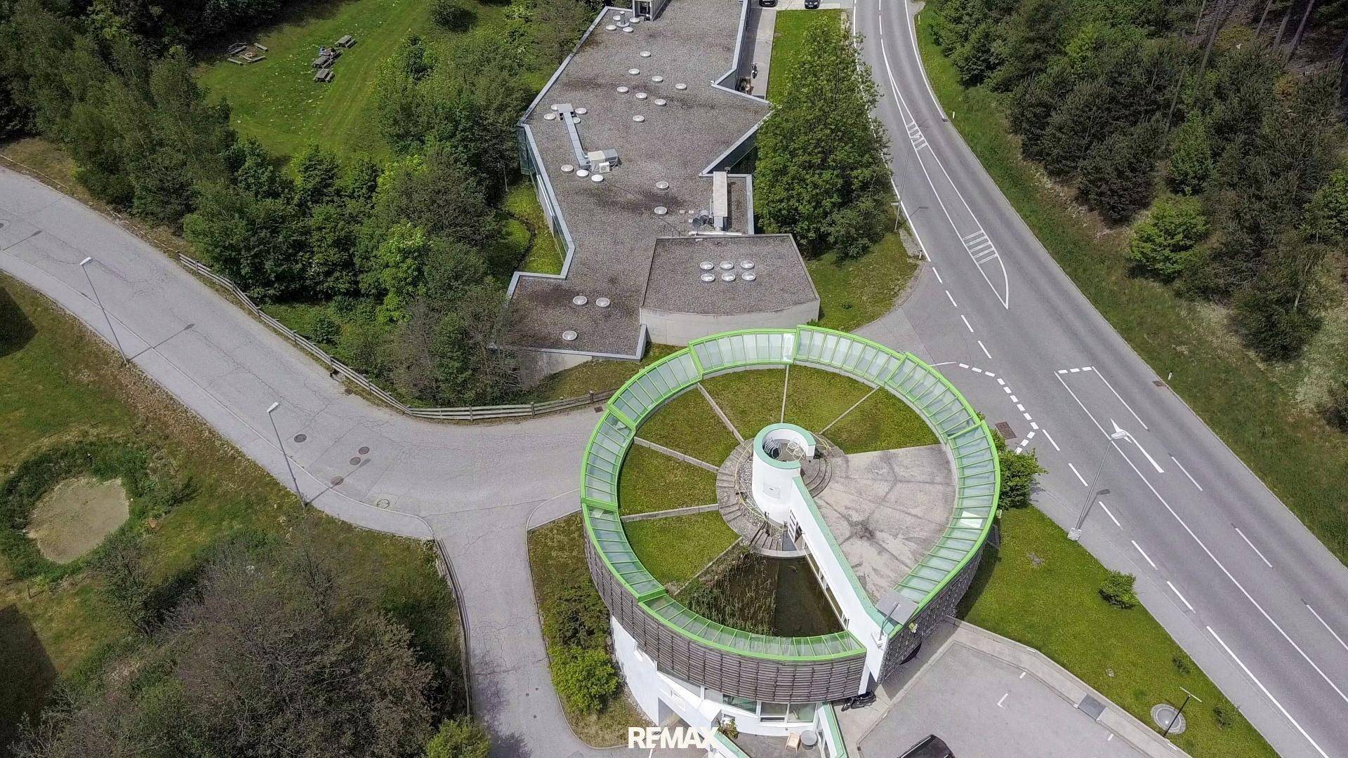 Luftaufnahme des Gebäudekomplexes mit markantem Rundbau und ausgedehnten begrünten Dachflächen.
