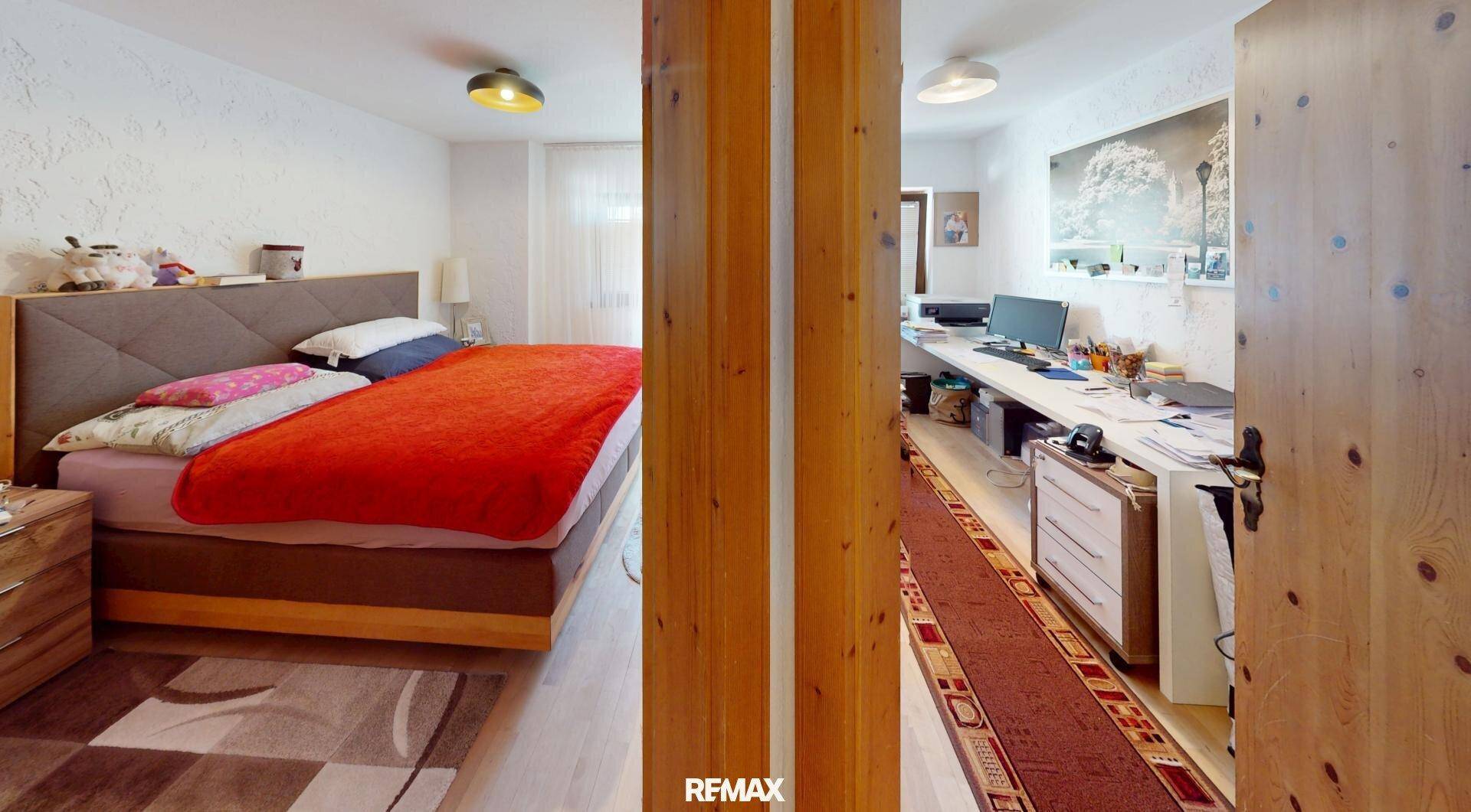 Schlafzimmer mit großem Bett, Holzelementen und einem angrenzenden Arbeitsbereich.