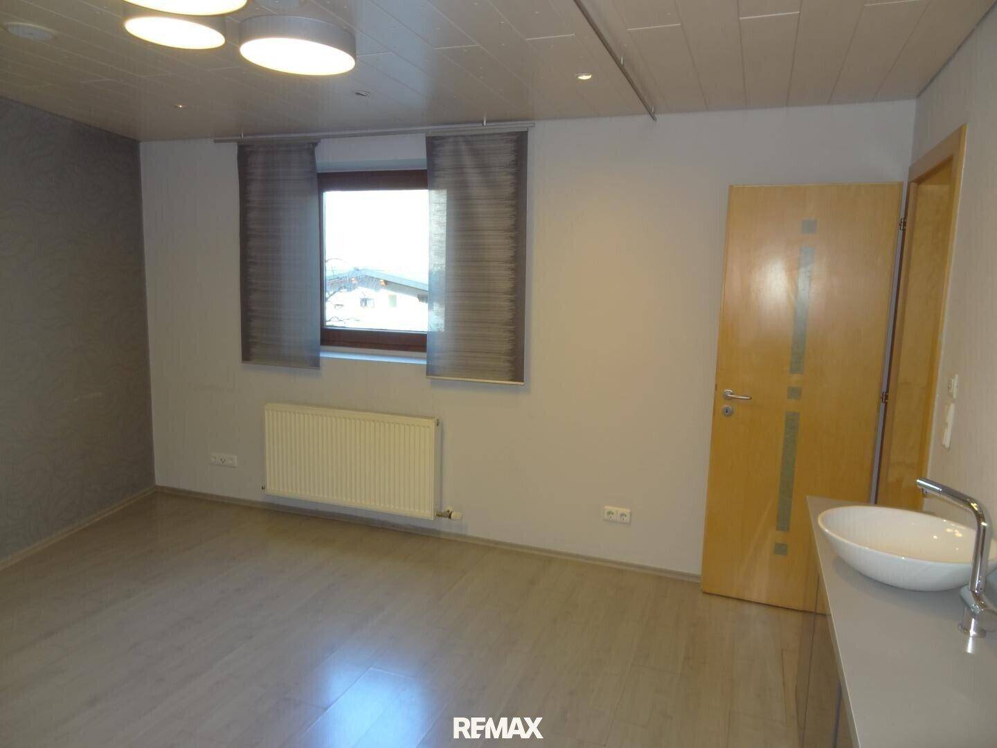 Helles Badezimmer mit modernem Waschbecken, Fenster und einem Heizkörper unter dem Fenster.