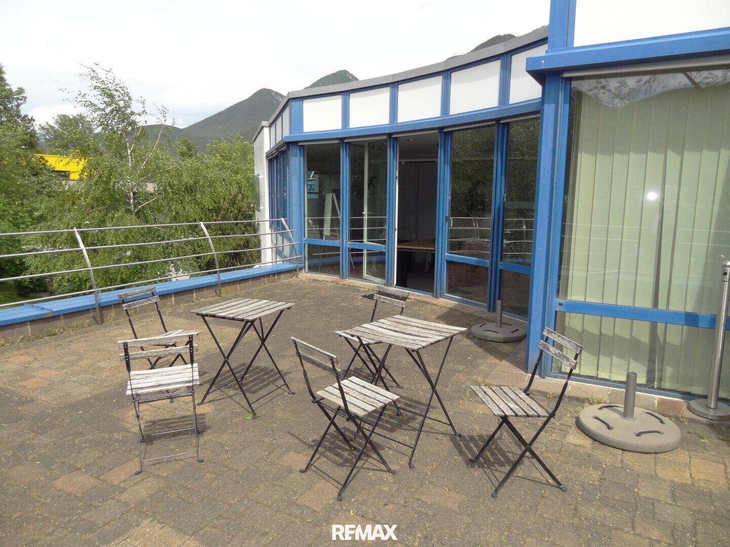 Dachterrasse mit einfachen Gartenmöbeln und Blick auf die umliegende Berglandschaft.