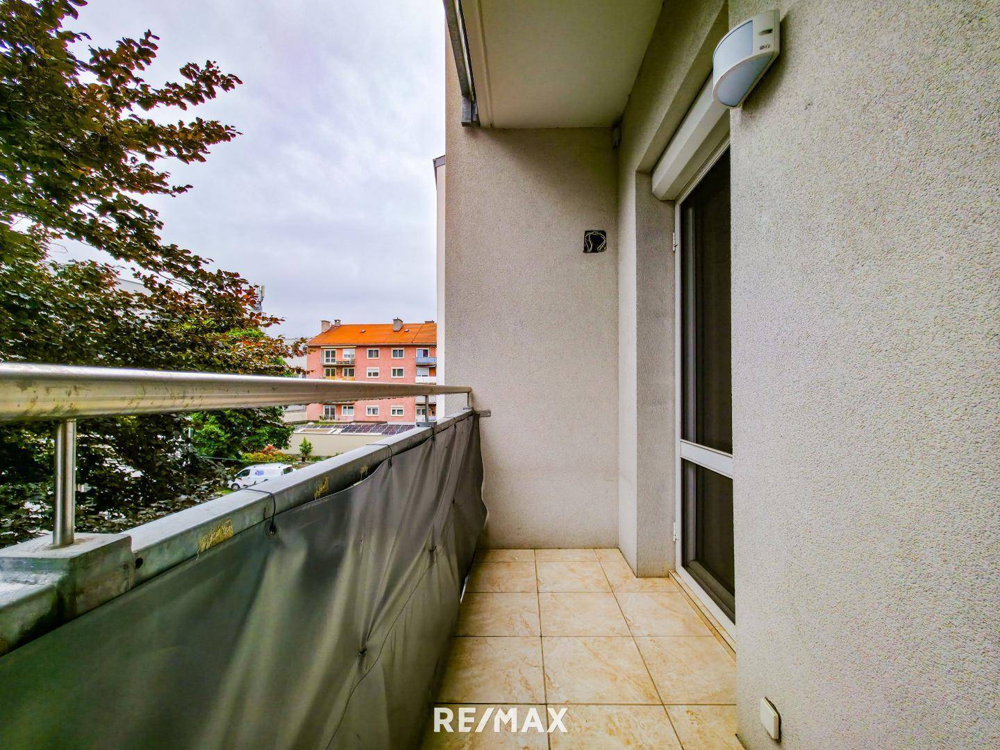 Kleiner Balkon mit Fliesenboden und Metallgeländer.