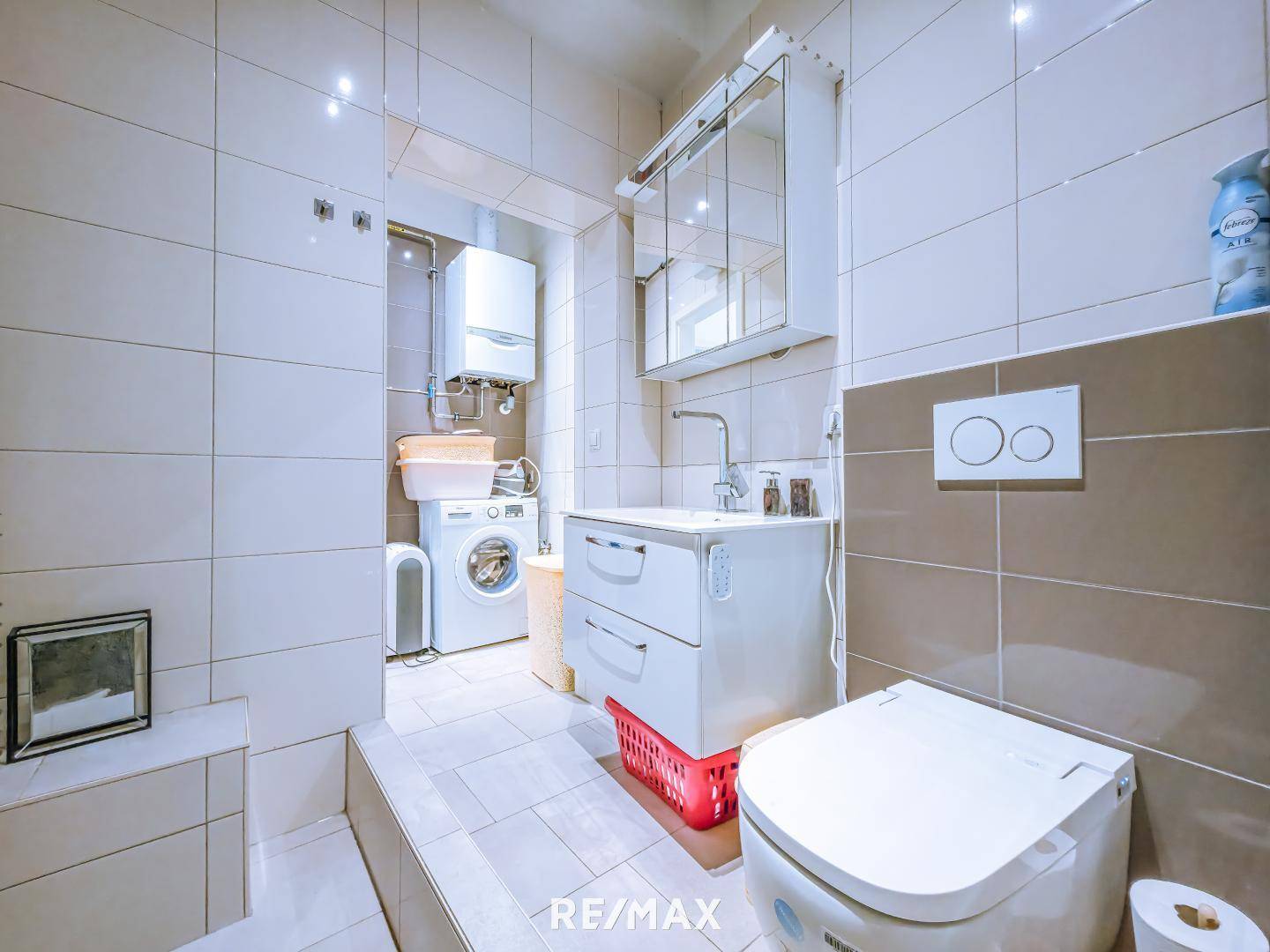 Badezimmer mit Waschmaschine, Toilette und Waschbecken.