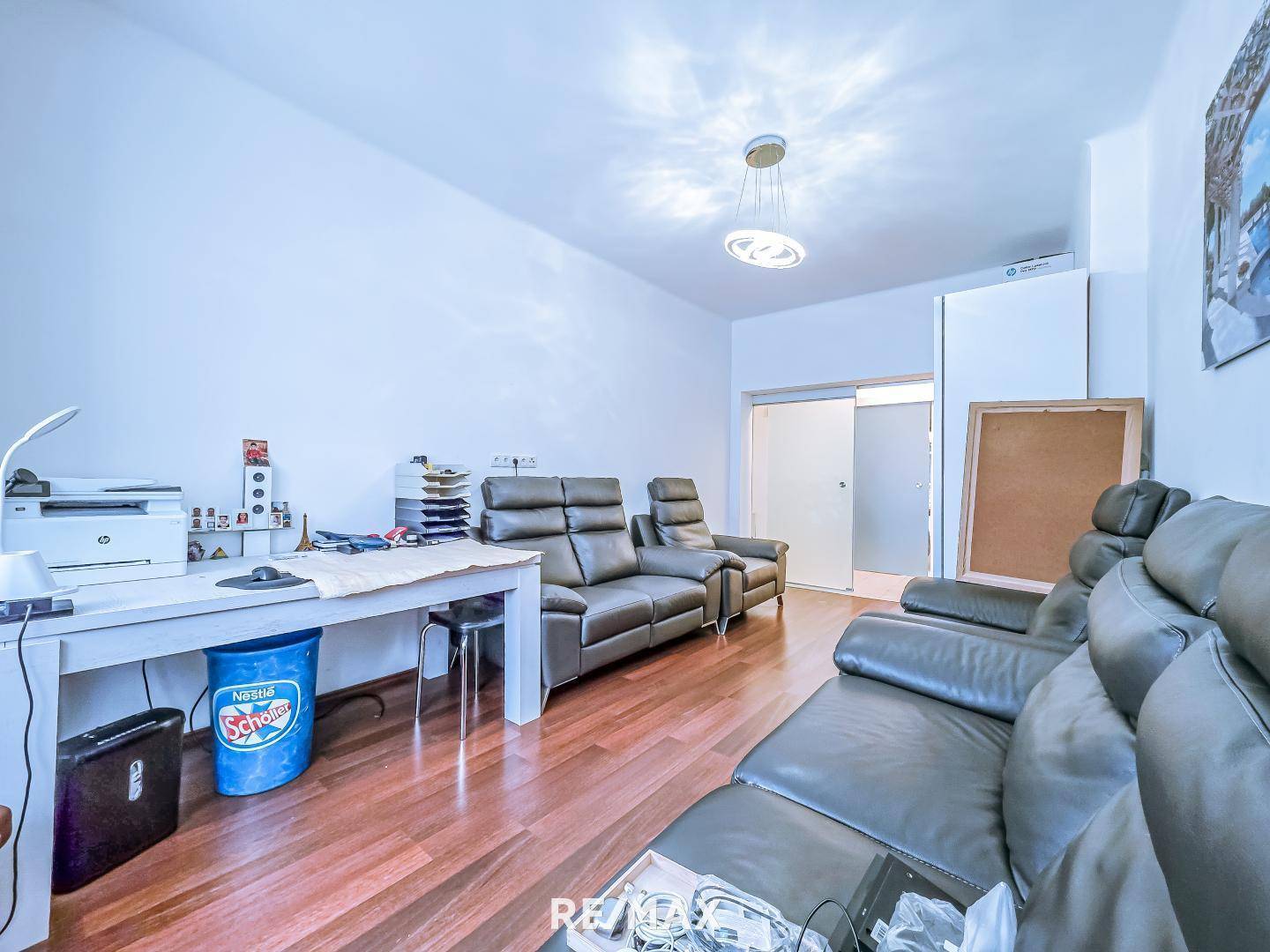 Arbeitsbereich mit Schreibtisch, Drucker und Ledersofas.