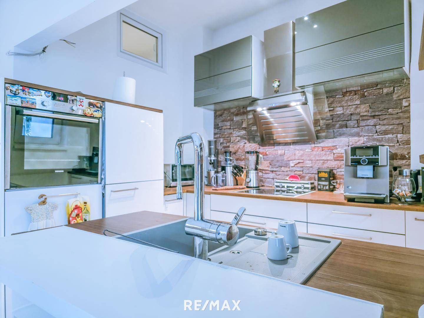 Moderne Küche mit Spüle, Kaffeemaschine und integrierten Geräten.