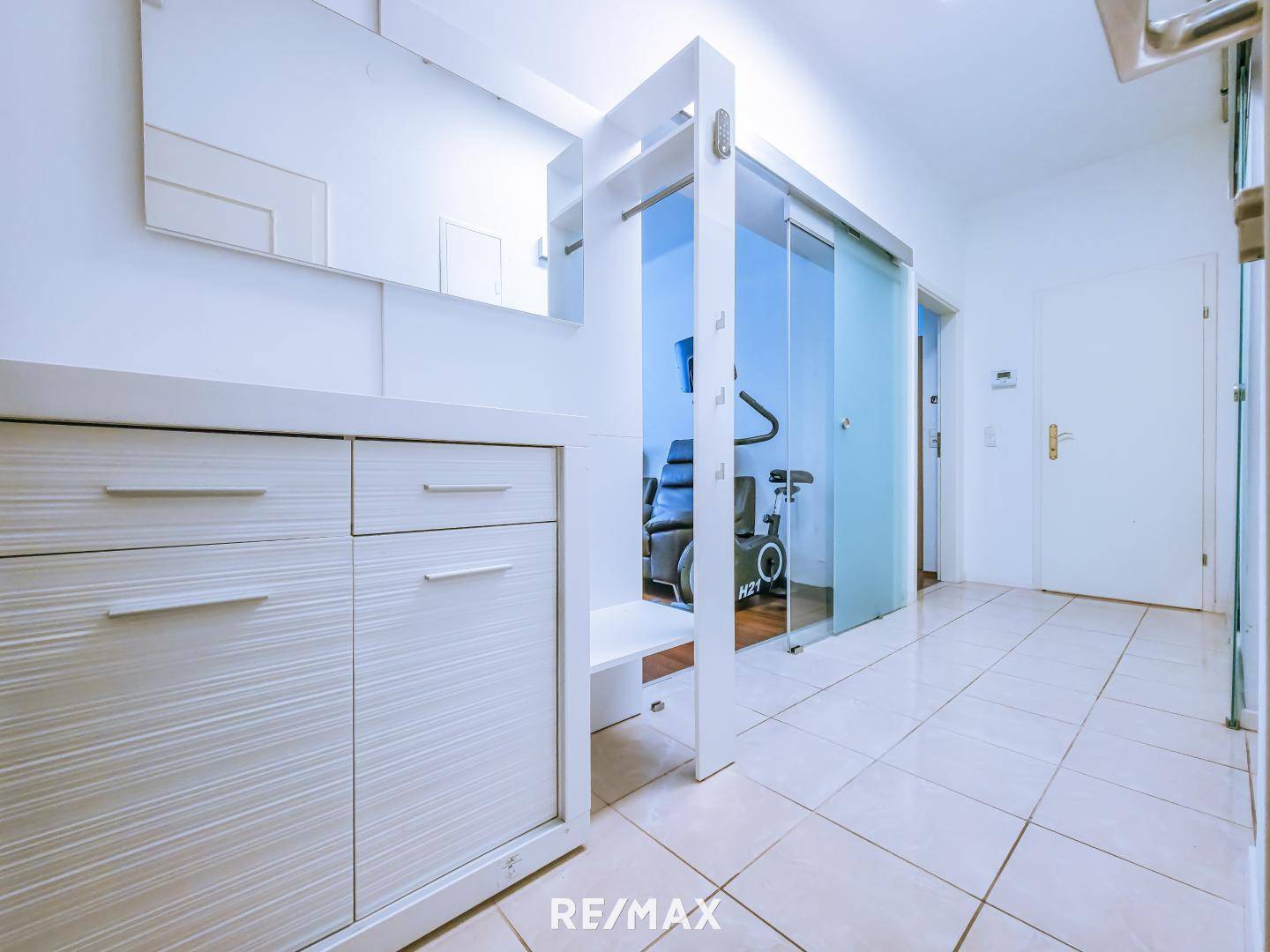 Eingangsbereich mit Fliesenboden, Garderobe und Spiegel.