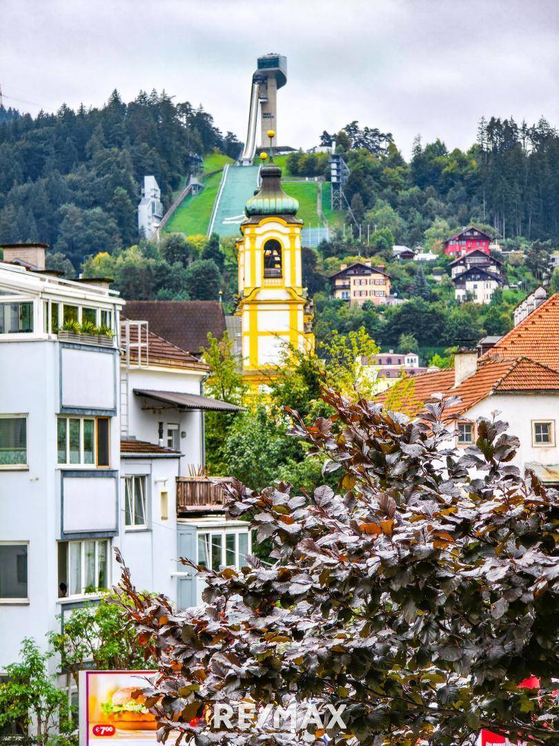 Panoramablick auf die Stadt mit Bergkulisse und Skisprungschanze.