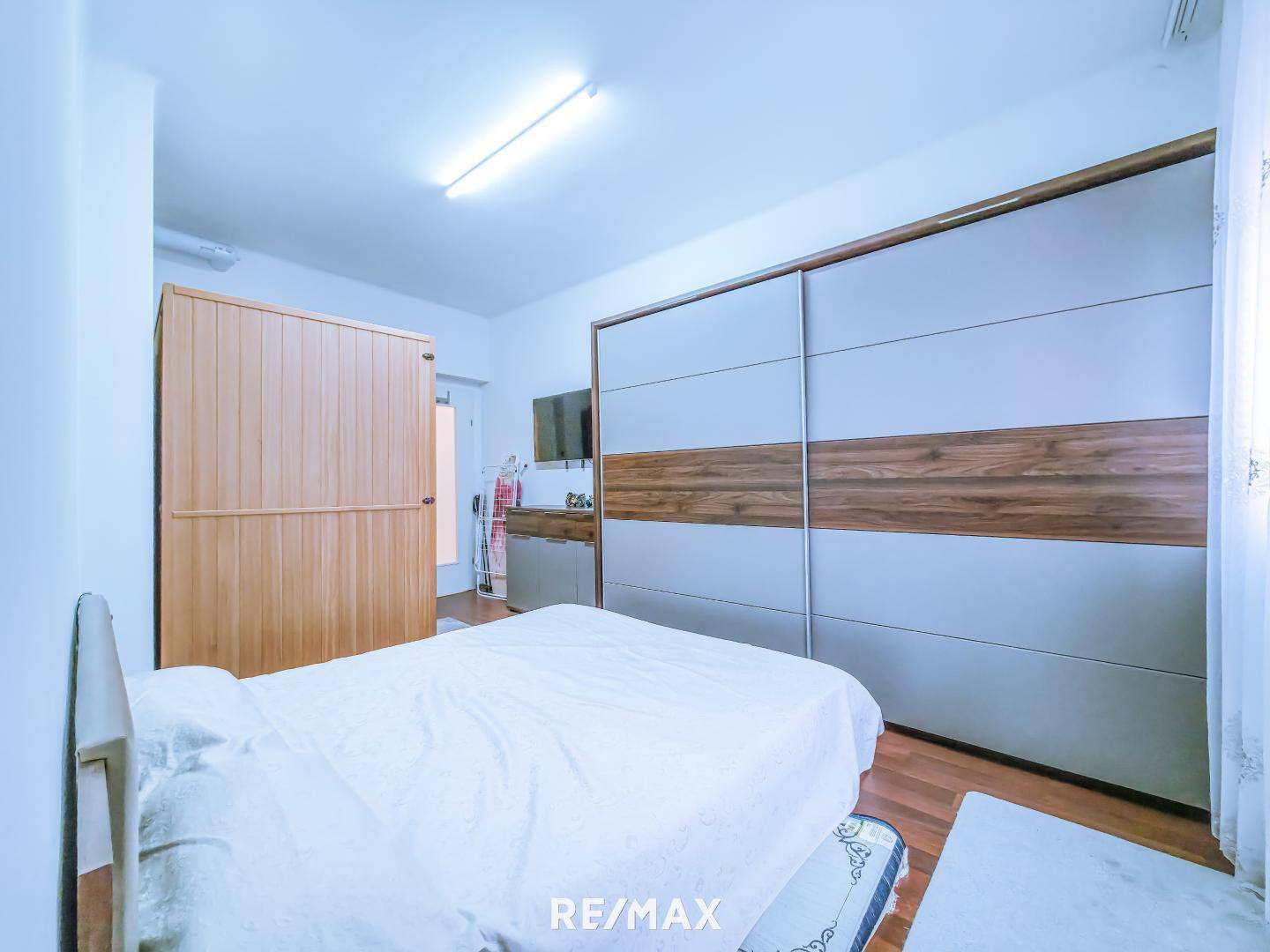 Schlafzimmer mit großem Schiebetürenschrank und Holzboden.