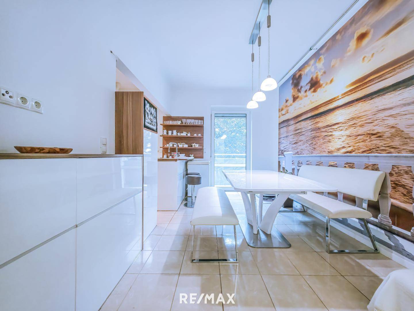 Heller Essbereich in der Küche mit großem Wandbild und Zugang zum Außenbereich.
