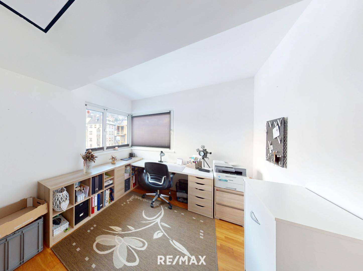 Funktionales Heimbüro mit Schreibtisch, Regalen und Blick nach draußen.