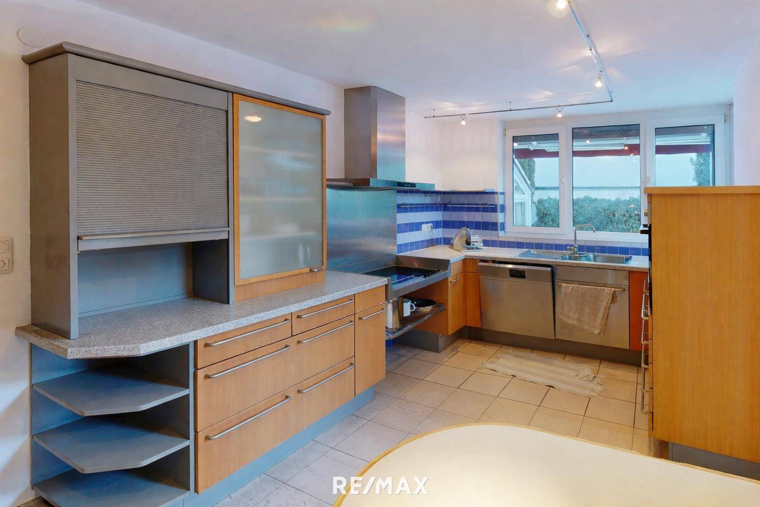 Funktionale Küche mit Granitarbeitsplatten, Fliesenboden und integrierten Geräten.