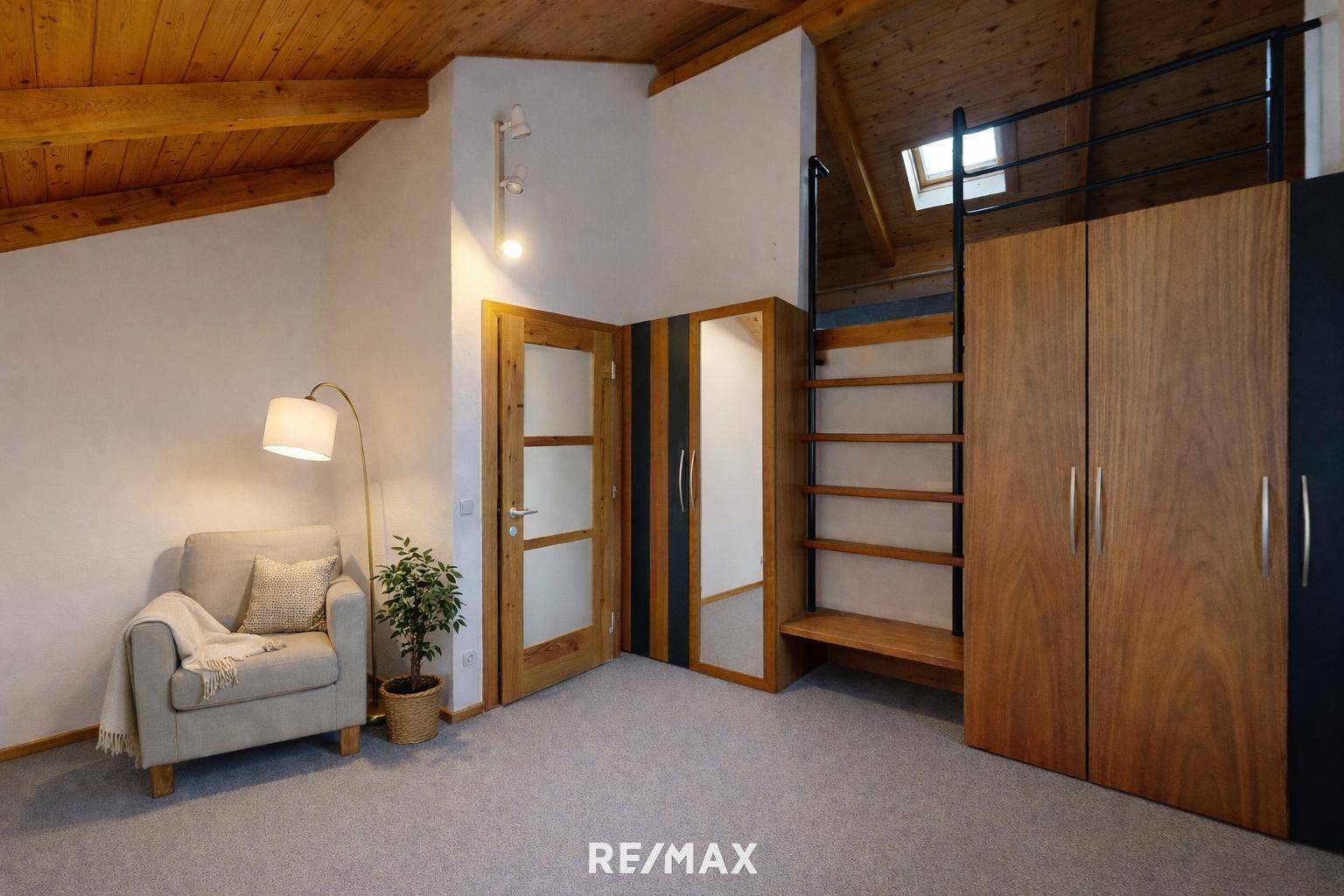 Gemütliches Dachzimmer mit Holzbalkendecke, Teppichboden und integrierten Schränken.