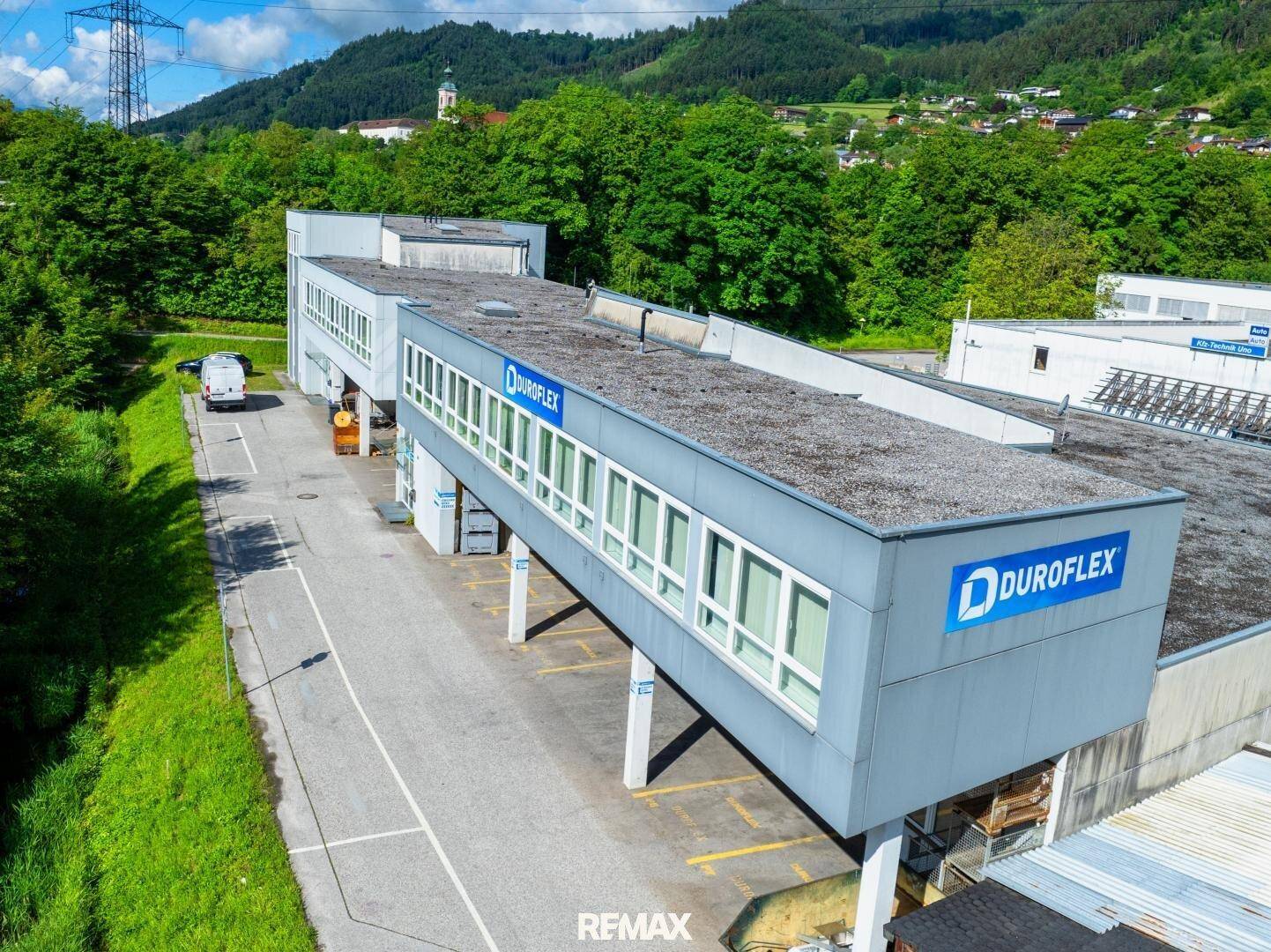 Drohnenansicht des Gewerbegebäudes mit DUROFLEX-Beschriftung, erhöhter Struktur und umgebender grüner Landschaft.