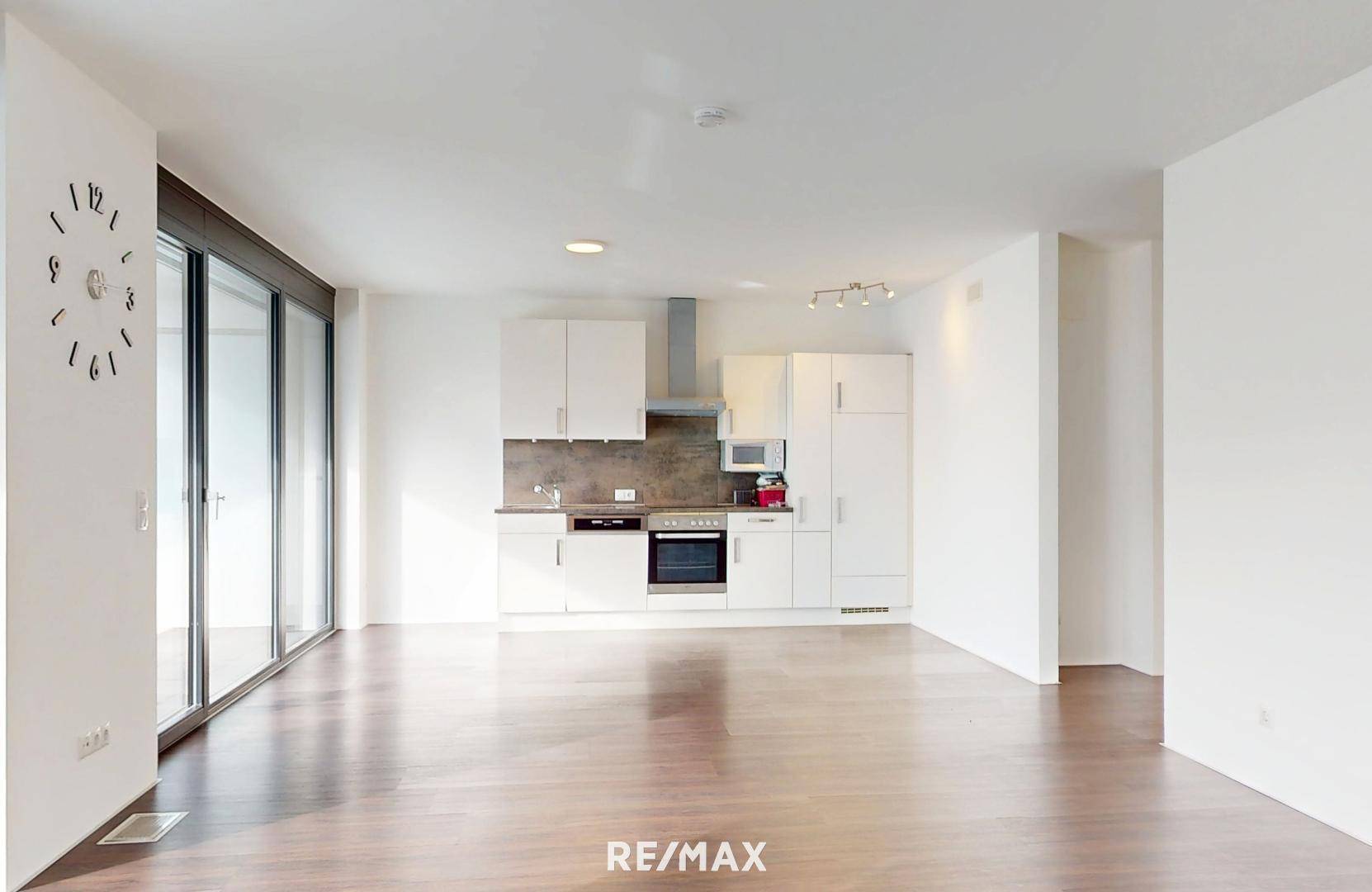 Offener Wohnbereich mit integrierter Küchenzeile und Holzboden.