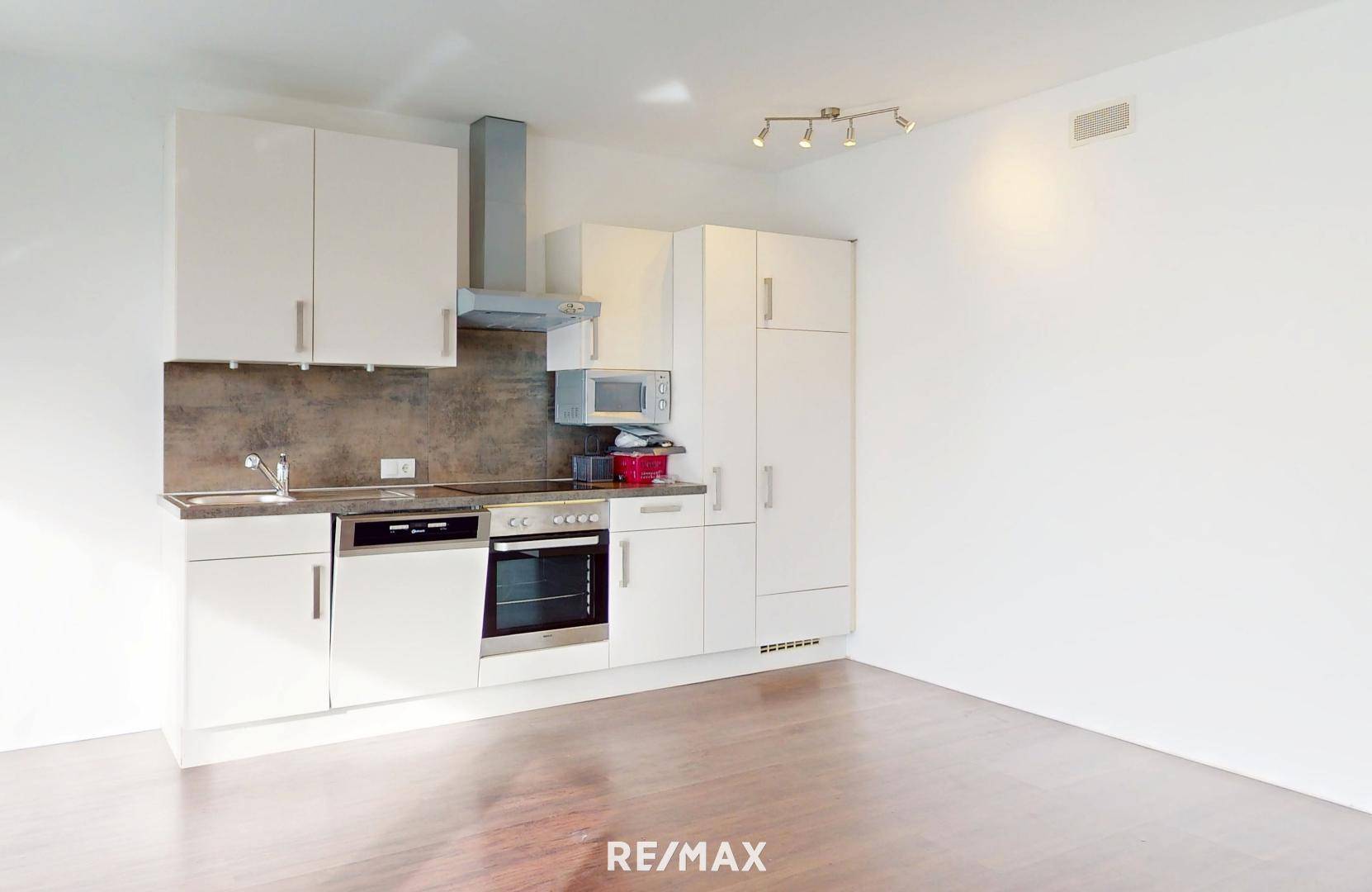 Kompakte, moderne Küchenzeile mit weißen Schränken und integrierten Geräten.