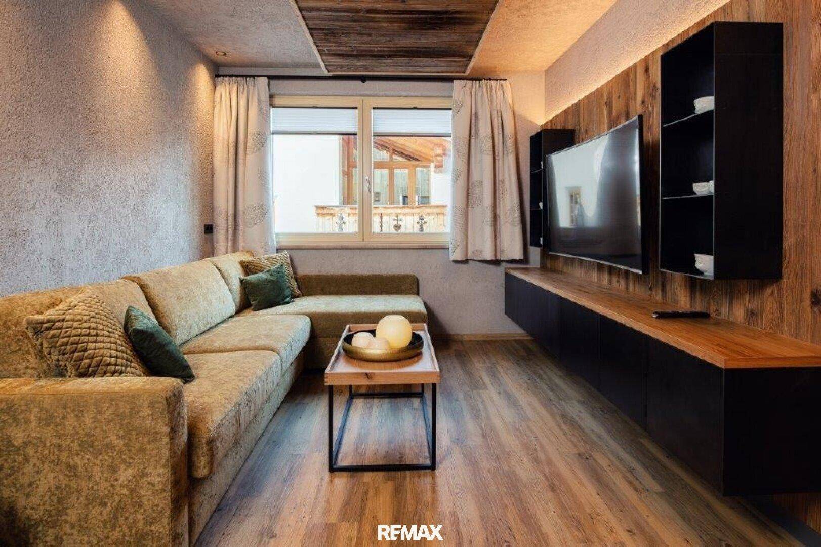 Gemütliches Wohnzimmer mit großem Ecksofa, Holzboden und einer modernen TV-Wand mit Holzverkleidung.