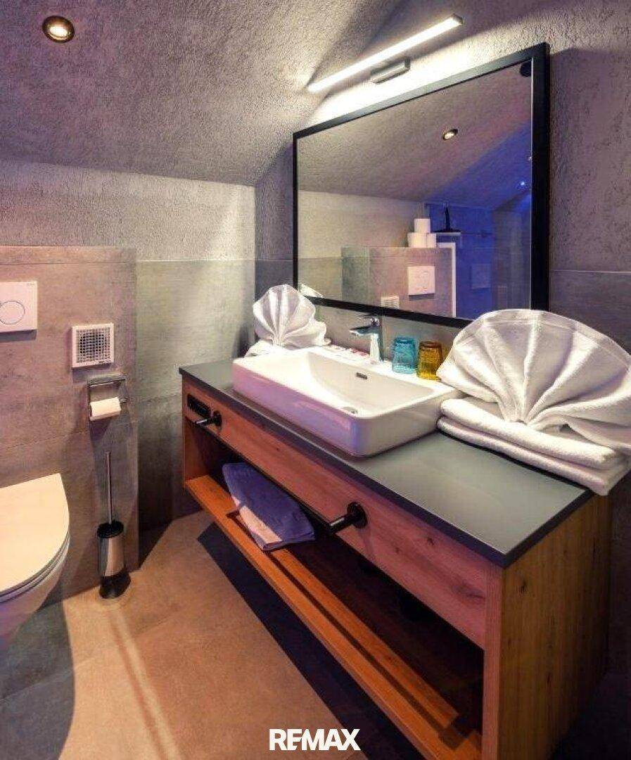Modernes Badezimmer mit Einzelwaschbecken auf Holzunterschrank und wandhängendem WC.