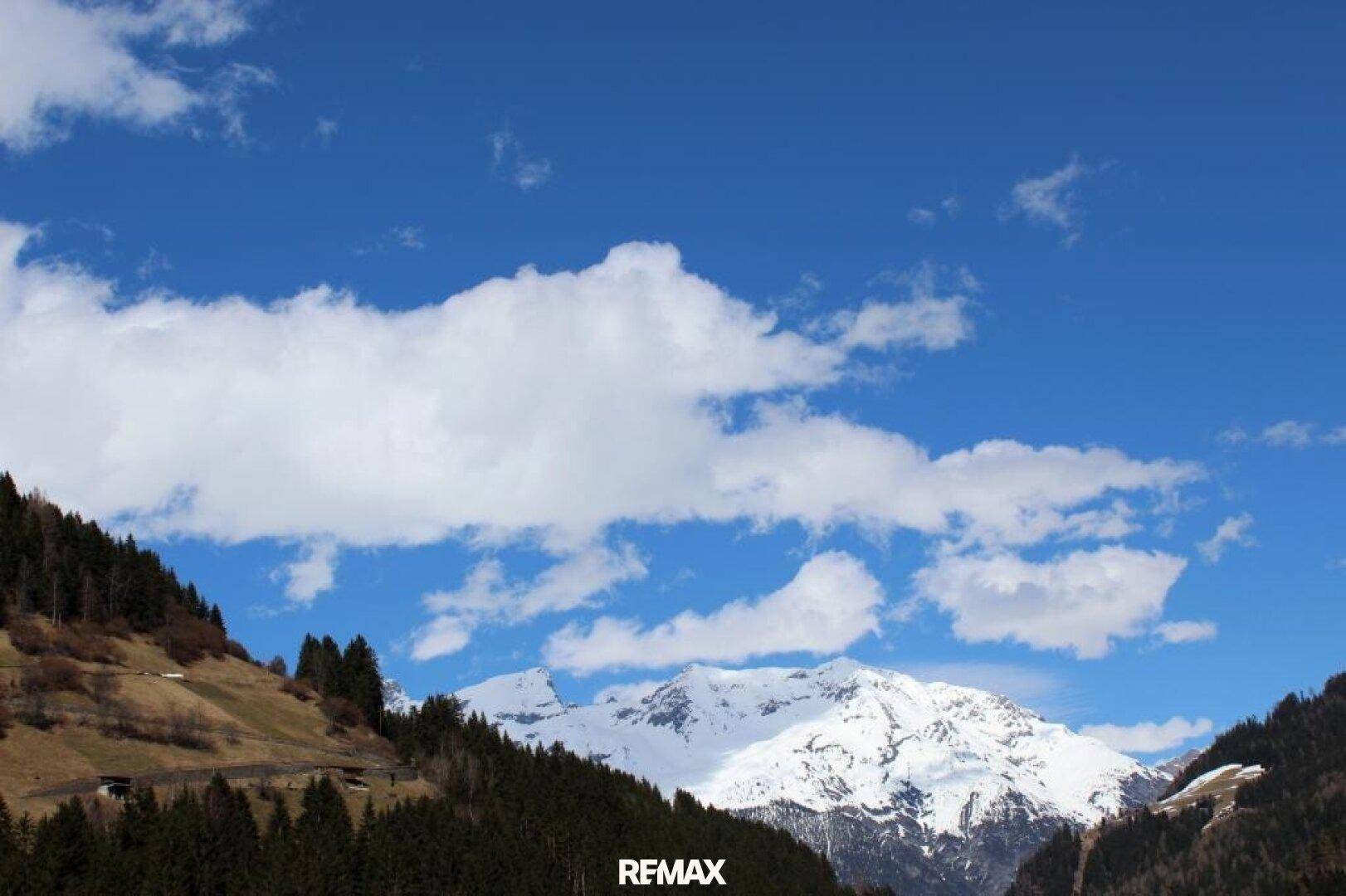 Majestätische schneebedeckte Berge unter einem strahlend blauen Himmel mit weißen Wolken.