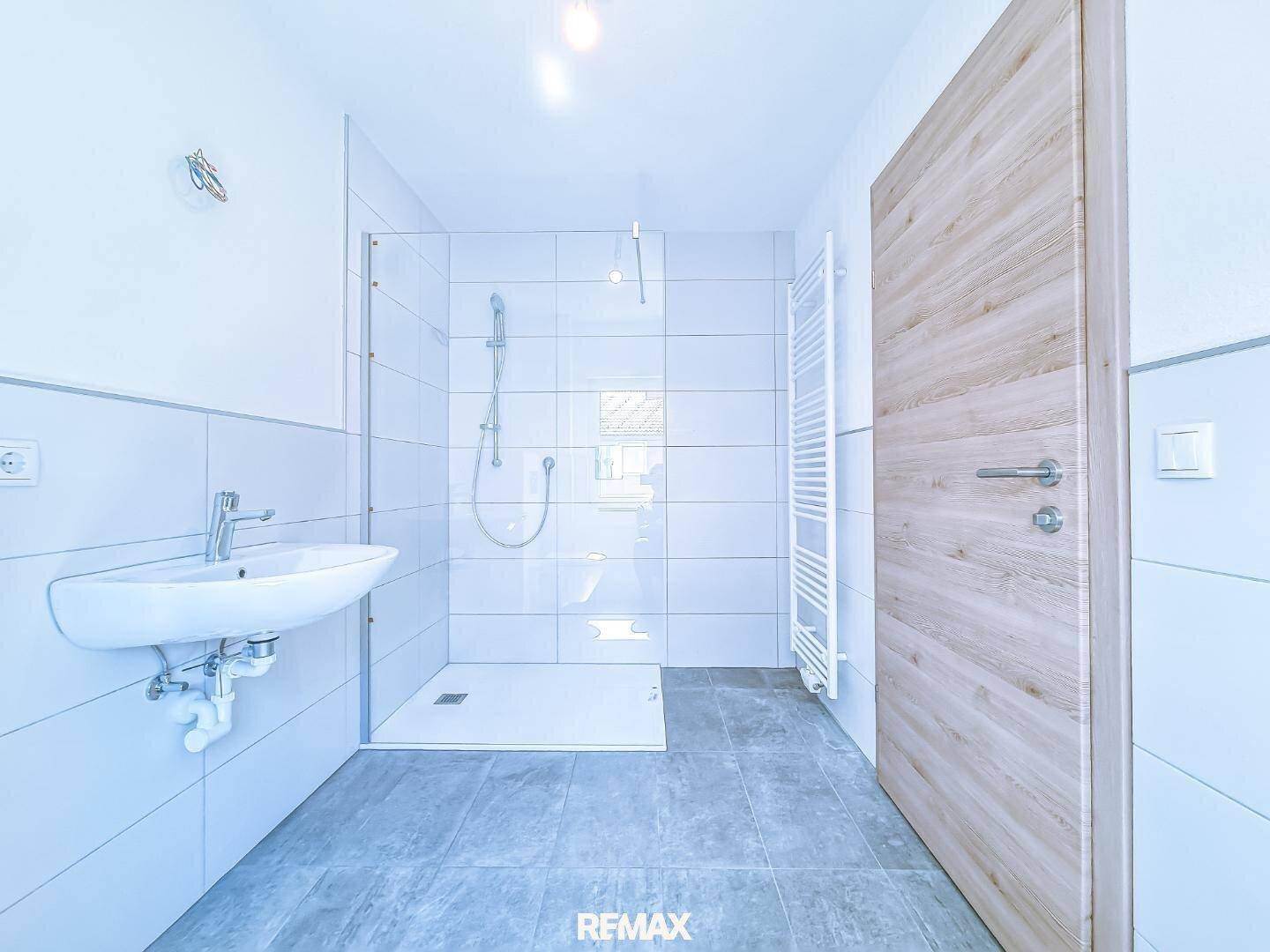 Modernes Badezimmer mit Duschkabine, Waschbecken und beheiztem Handtuchhalter.