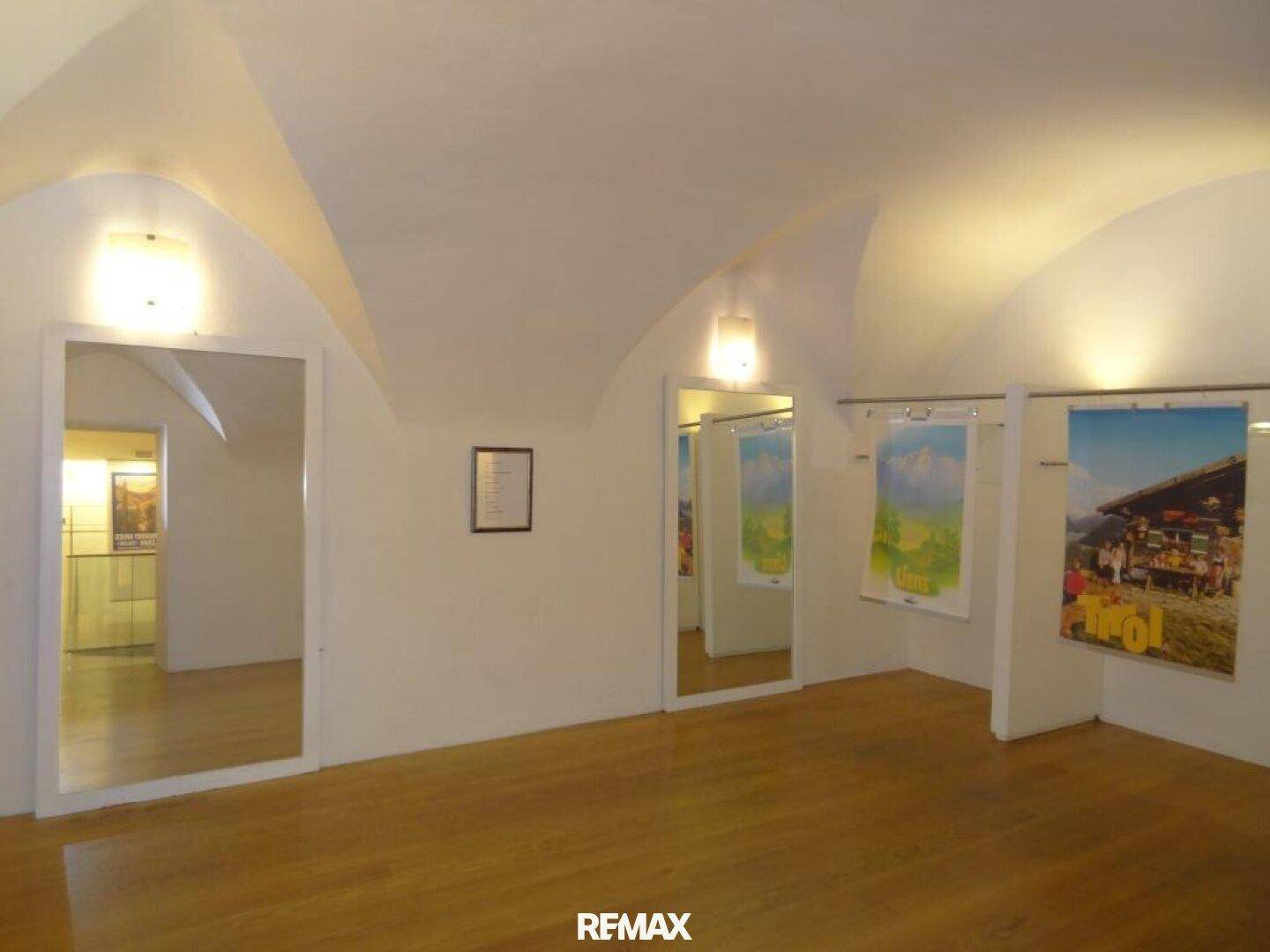 Raum mit gewölbter Decke, Holzfußboden und großen Spiegeln, der als Galerie genutzt wird.