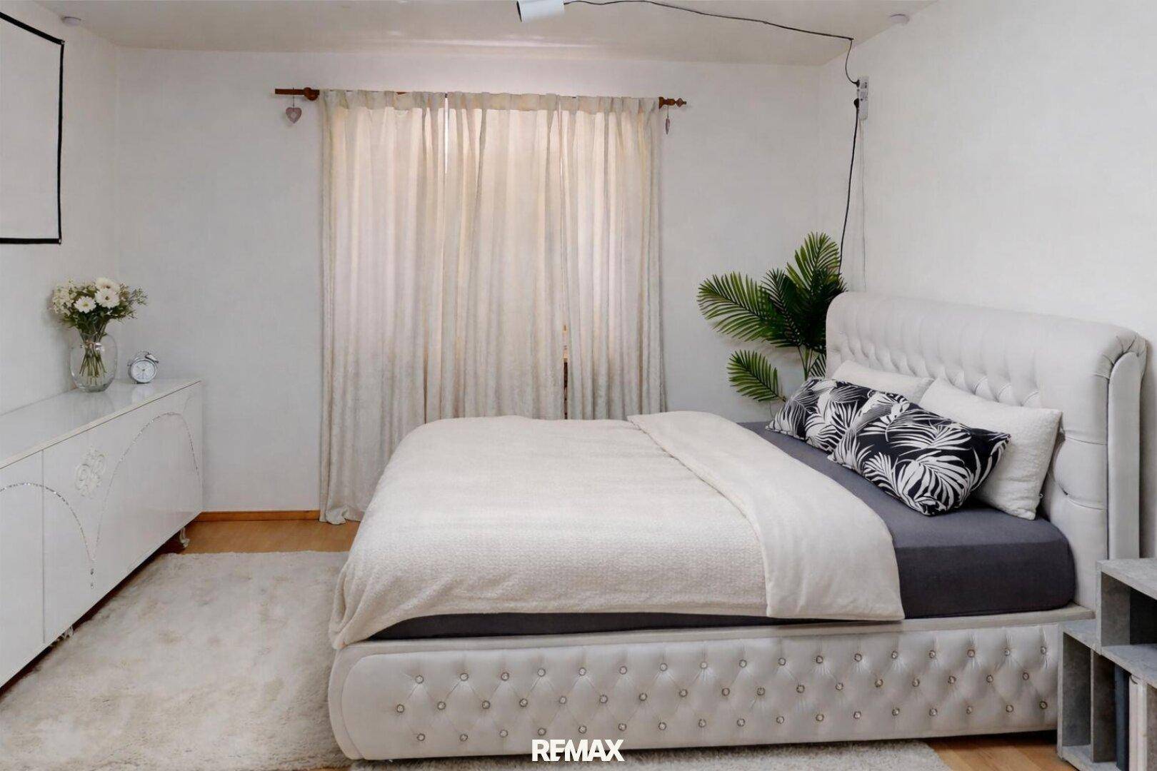 Helles Schlafzimmer mit großem Bett, weißer Kommode und Vorhängen für eine ruhige Atmosphäre.
