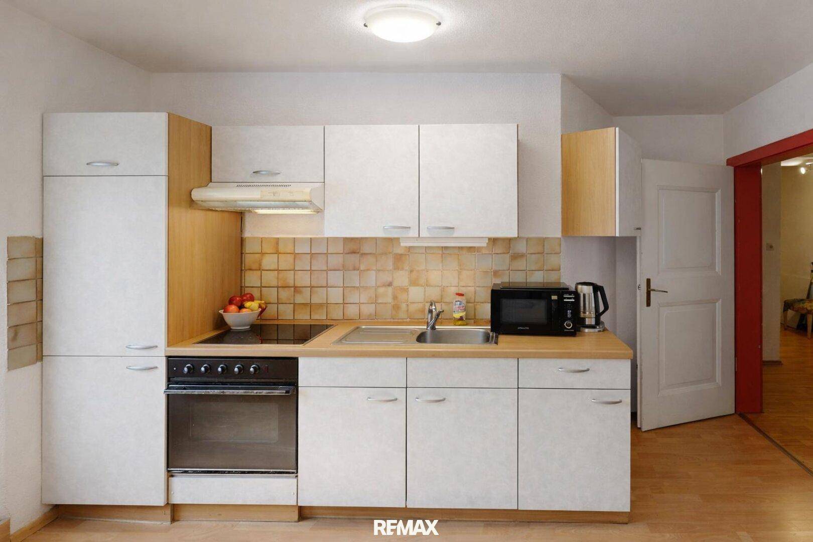 Funktionale Einbauküche mit weißen Fronten, Backofen und Fliesenspiegel für den täglichen Gebrauch.
