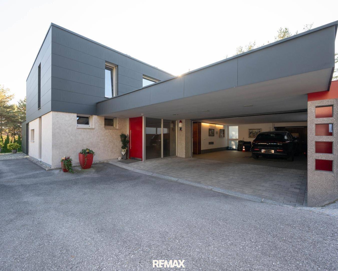 Eingangsbereich der modernen Villa mit überdachtem Carport und breiter Zufahrt.