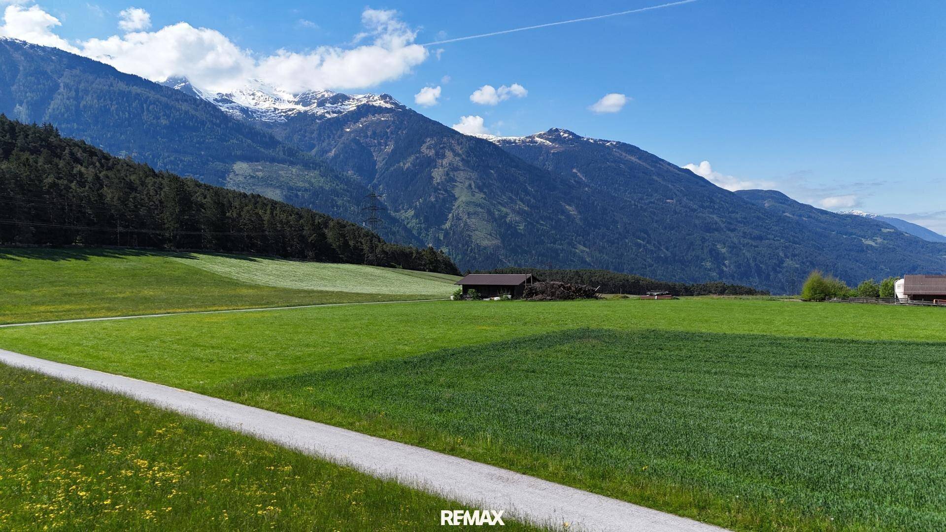 Malerische Berglandschaft mit grünen Wiesen und einem klaren blauen Himmel.