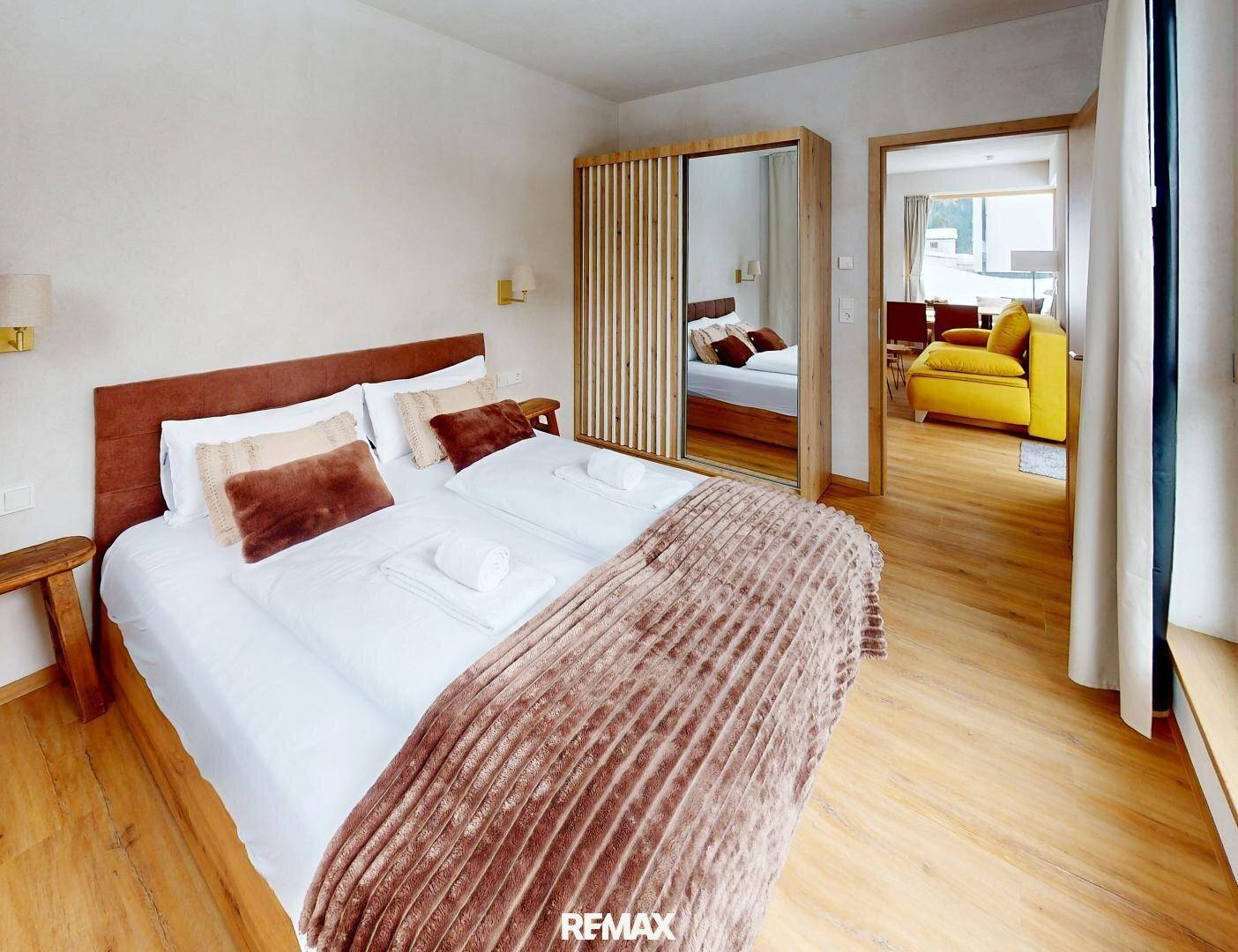 Komfortables Schlafzimmer mit Doppelbett und Zugang zu einem hellen Wohnbereich.