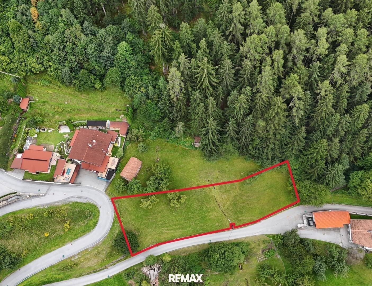 Luftaufnahme eines Grundstücks mit roter Umrandung, umgeben von Wald und ländlicher Bebauung.