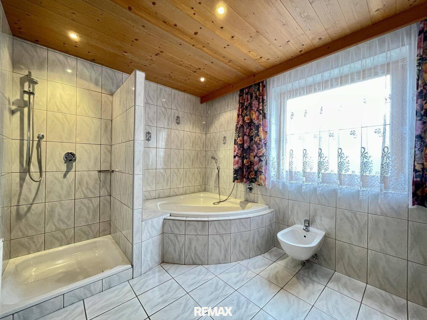 Geräumiges Badezimmer mit Eckbadewanne, Dusche, Bidet und Holzdecke.