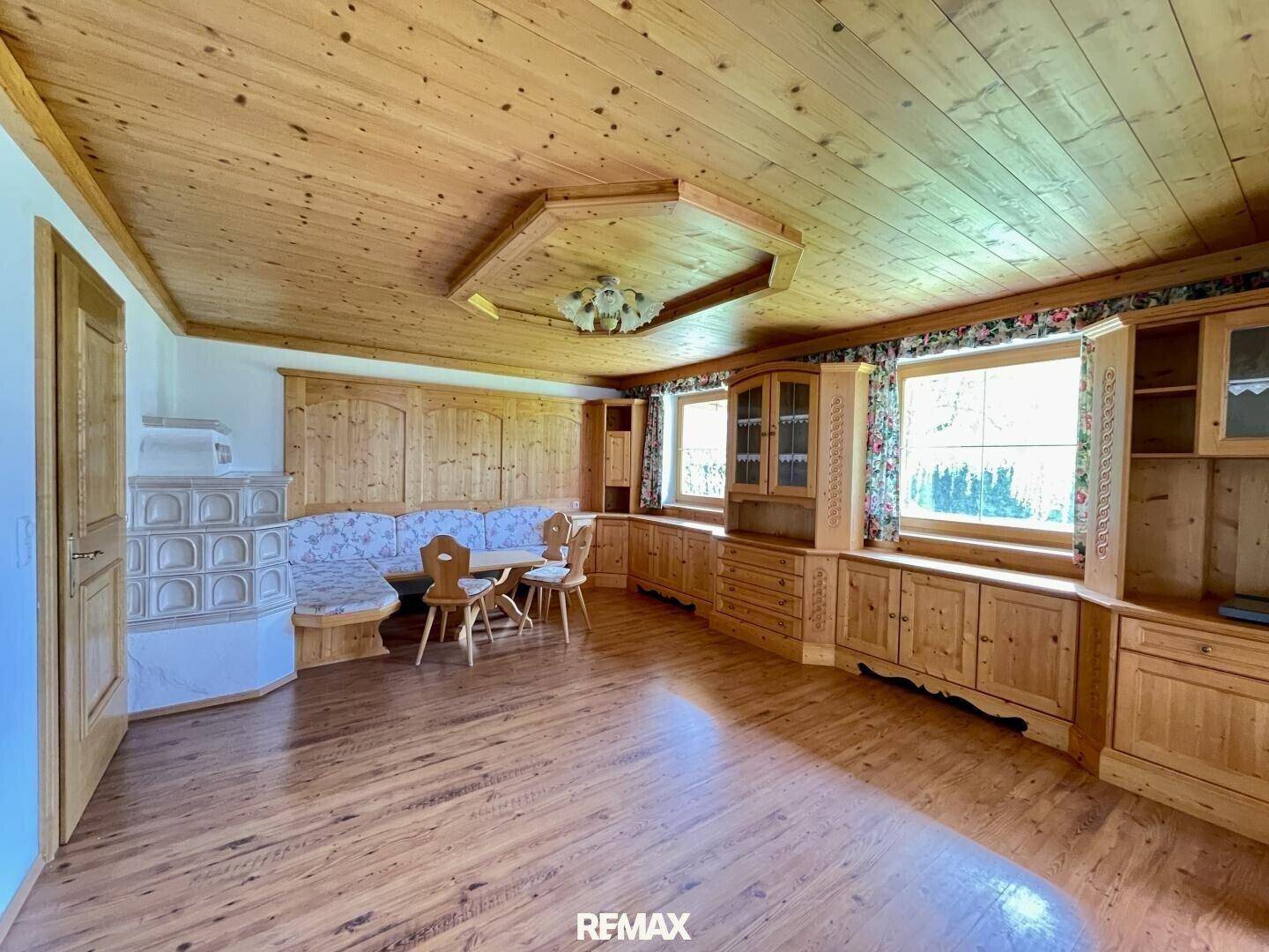 Gemütlicher Wohn- und Essbereich im alpenländischen Stil mit viel Holz und traditionellem Kachelofen.