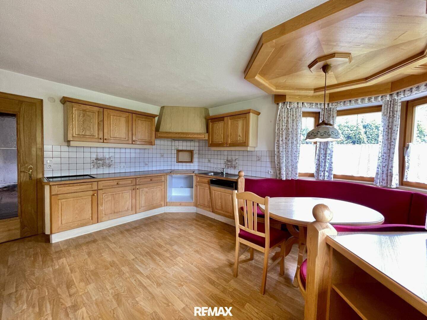 Traditionelle Holzküche mit Essecke und Blick ins Grüne durch die Fenster.