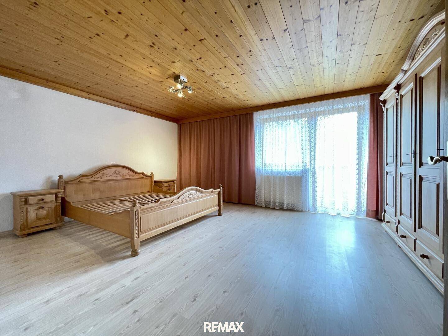 Geräumiges Schlafzimmer mit hellem Laminatboden und traditionellen Holzmöbeln.