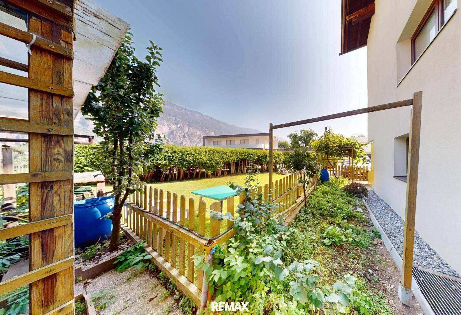 Gepflegter Gartenbereich mit Holzzaun, Grünflächen und einem kleinen Schuppen.