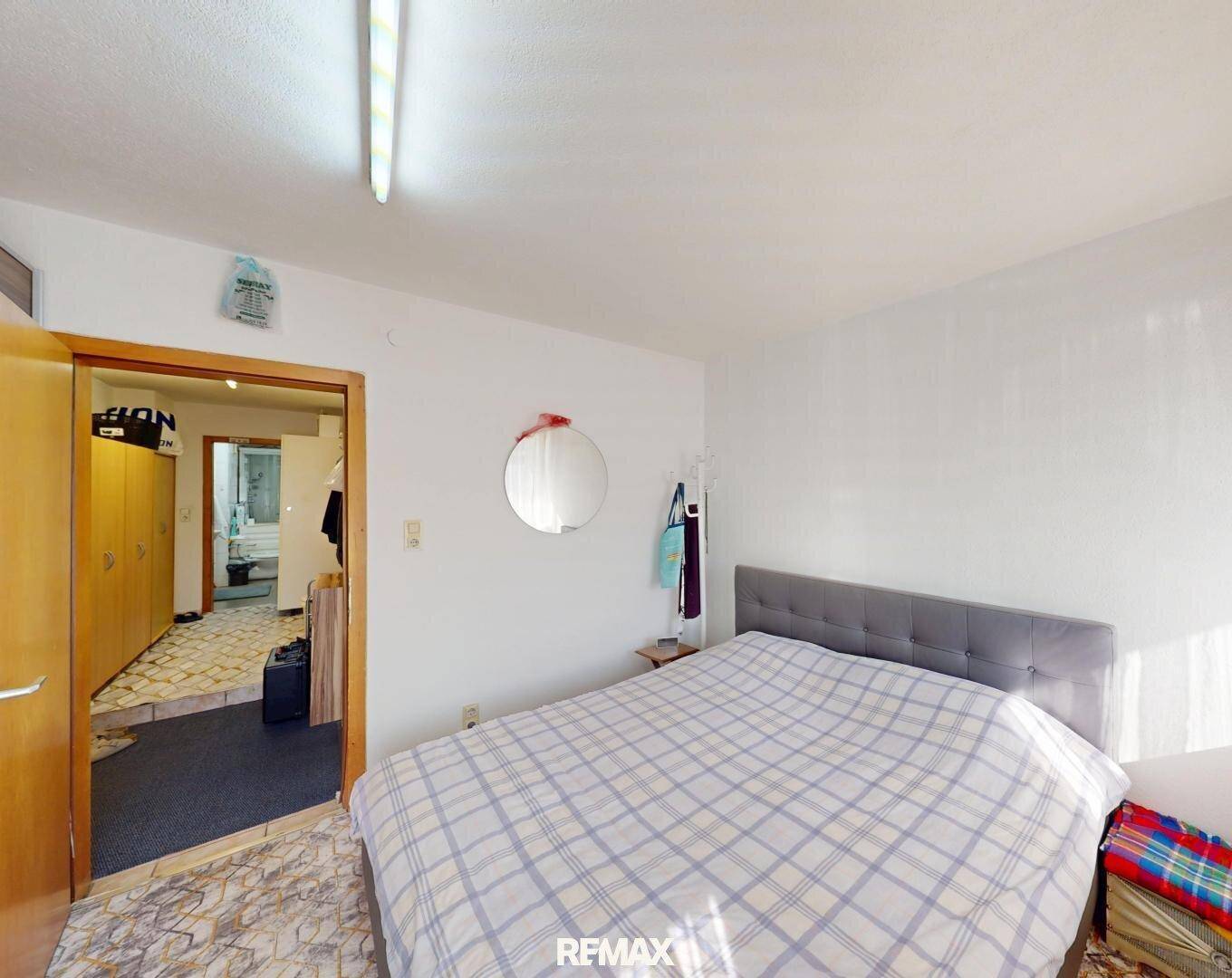 Schlafzimmer mit Doppelbett und Zugang zu einem gefliesten Flur.