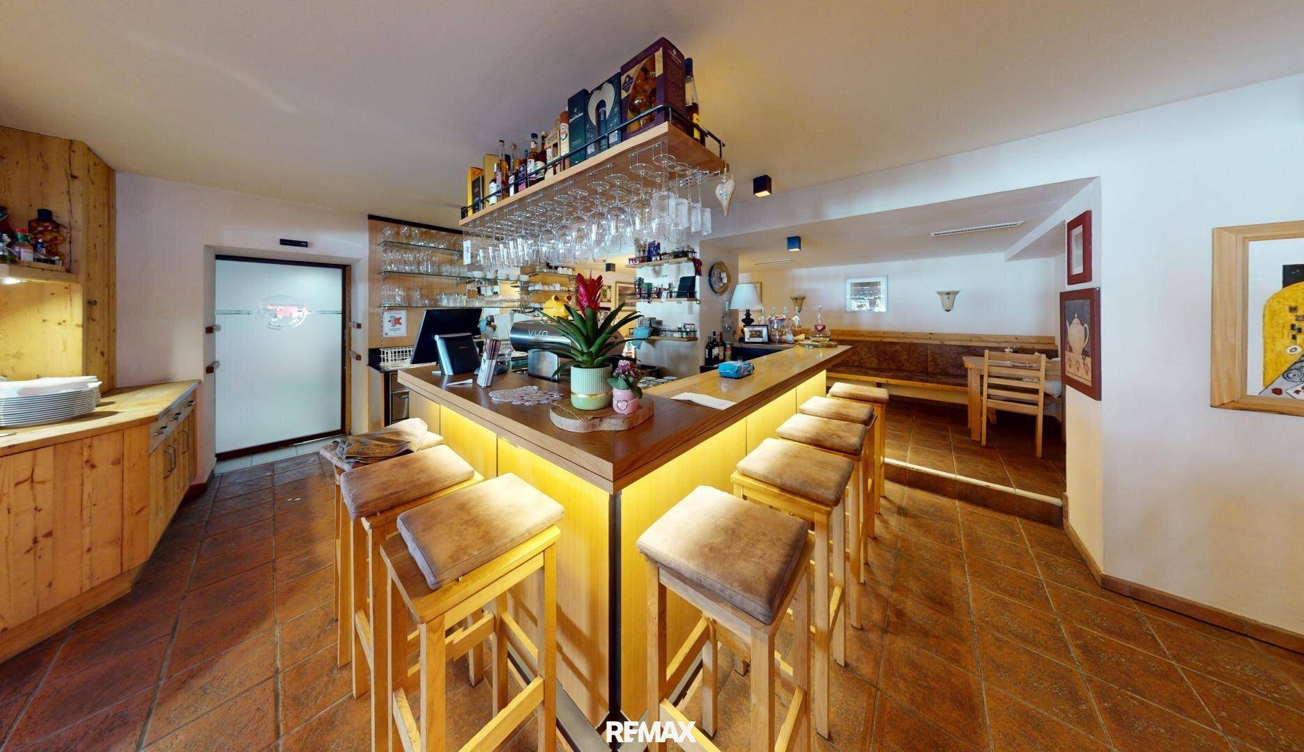 Gemütliche Bar mit Holztheke, Barhockern und rustikalen Fliesenböden, ideal für gesellige Abende.