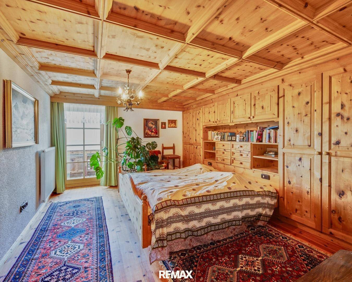 Großes Schlafzimmer mit Doppelbett, Holzeinbauten und Zugang zu einem Balkon.