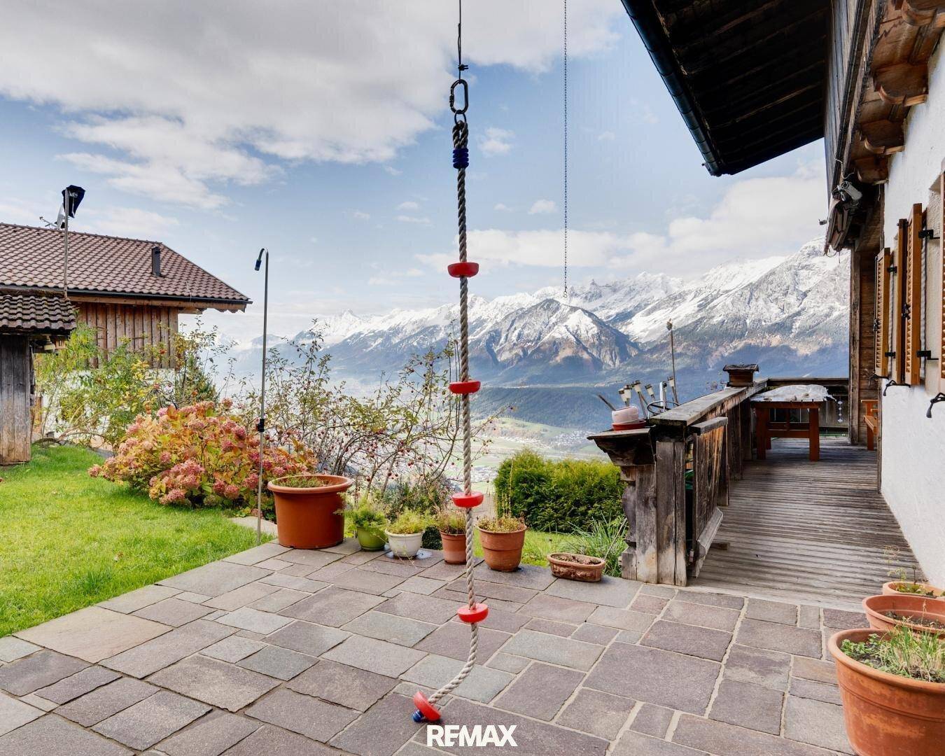 Gepflasterte Terrasse mit Bergblick, Blumentöpfen und einem Kletterseil für Kinder.