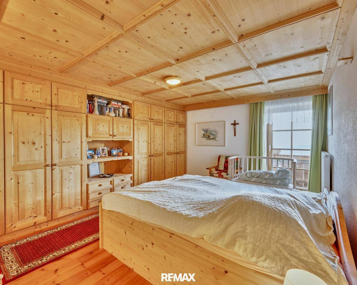 Schlafzimmer im traditionellen Stil mit Holzbett, Einbauschränken und Holzdecke.