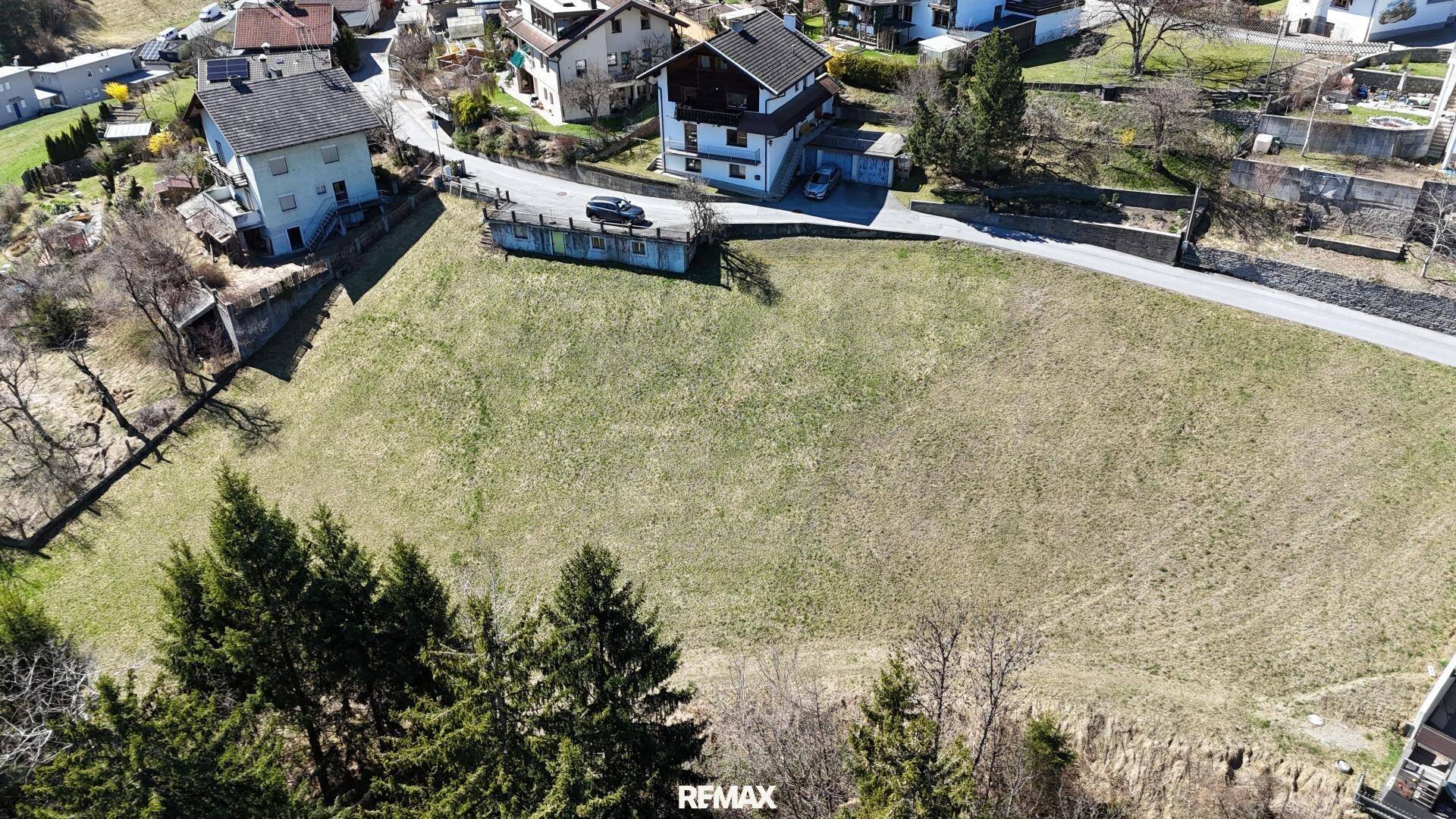 Übersichtliche Luftaufnahme eines weitläufigen Grundstücks mit angrenzenden Wohnhäusern und einer Straße.