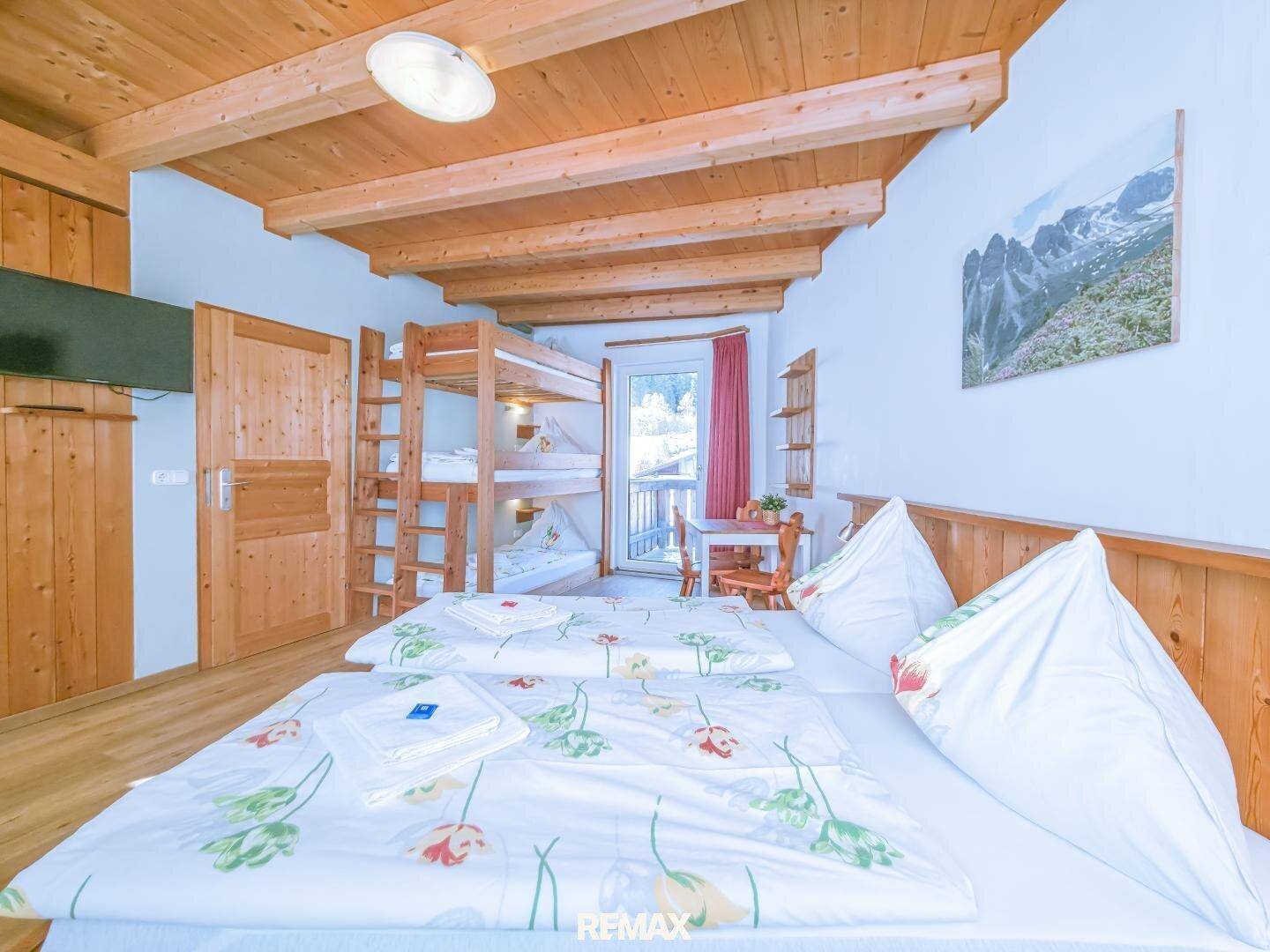 Geräumiges Schlafzimmer mit Doppelbett, Etagenbetten und Zugang zu einem Balkon.
