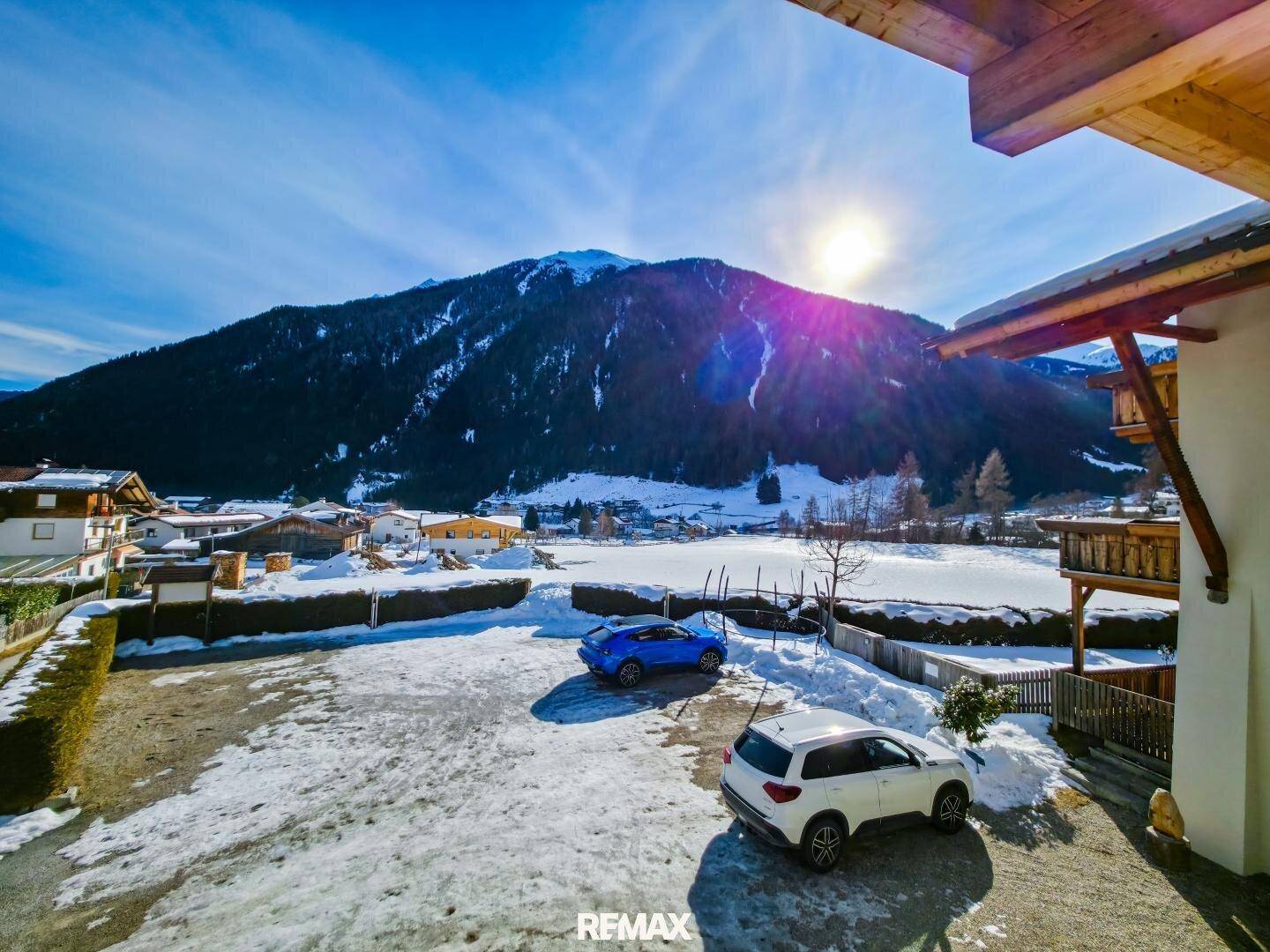 Außenansicht des Anwesens mit verschneitem Vorplatz und majestätischer Bergkulisse.